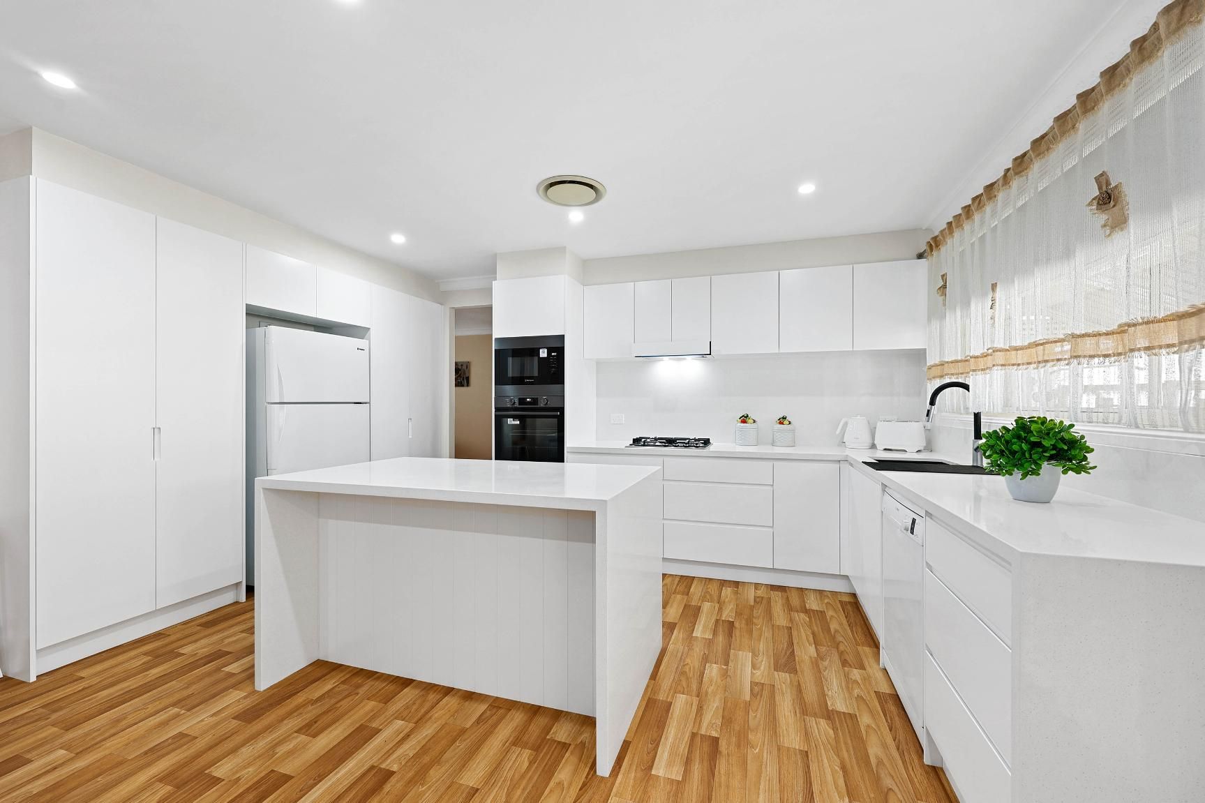 Modern, White Kitchen with Island, Appliances, and Wooden Floors — Above & Beyond Interiors Custom Joinery in Narellan Vale, NSW