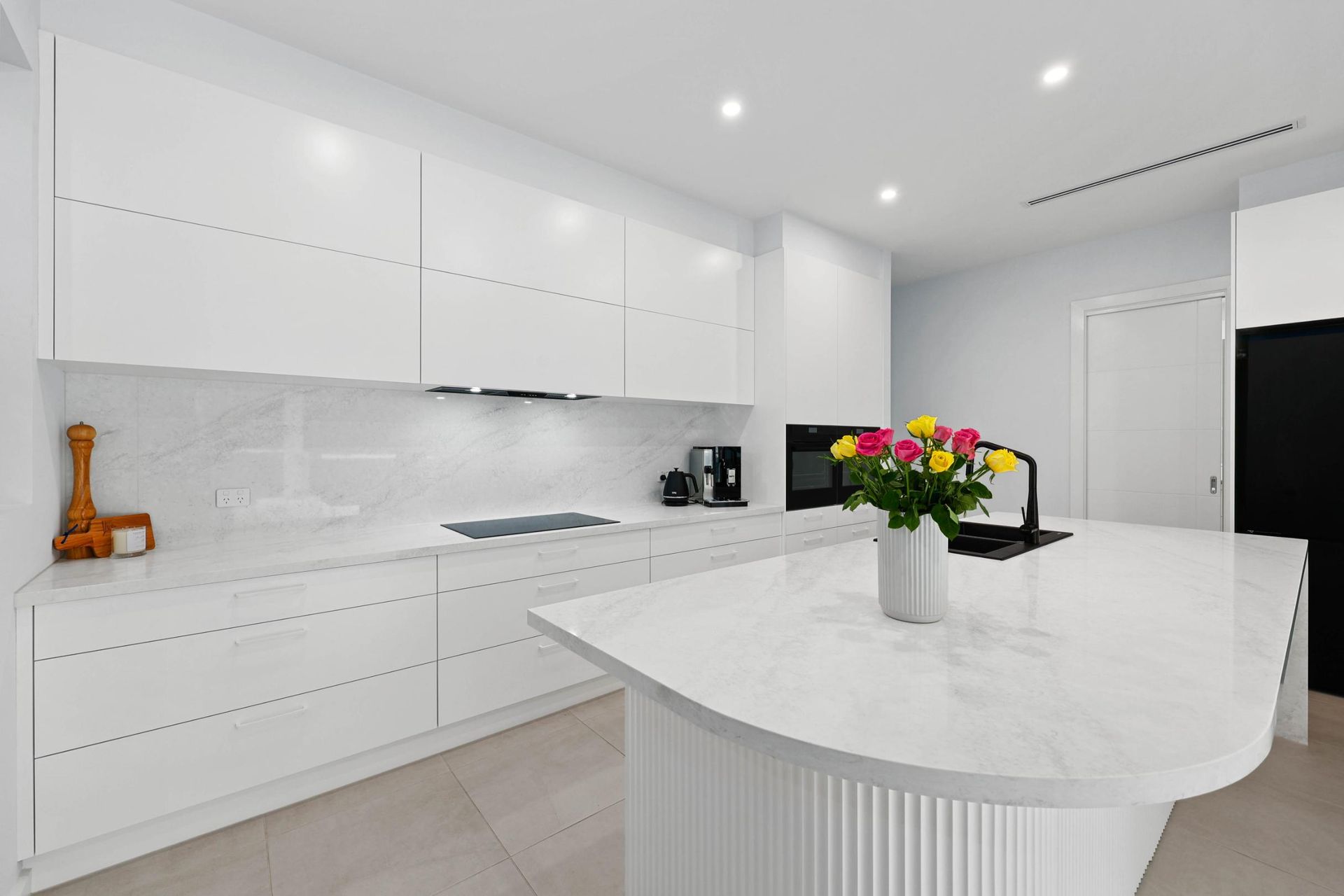 Modern White Kitchen with Island, Marble Countertops, and Colorful Flowers — Above & Beyond Interiors Custom Joinery in Currans Hill, NSW