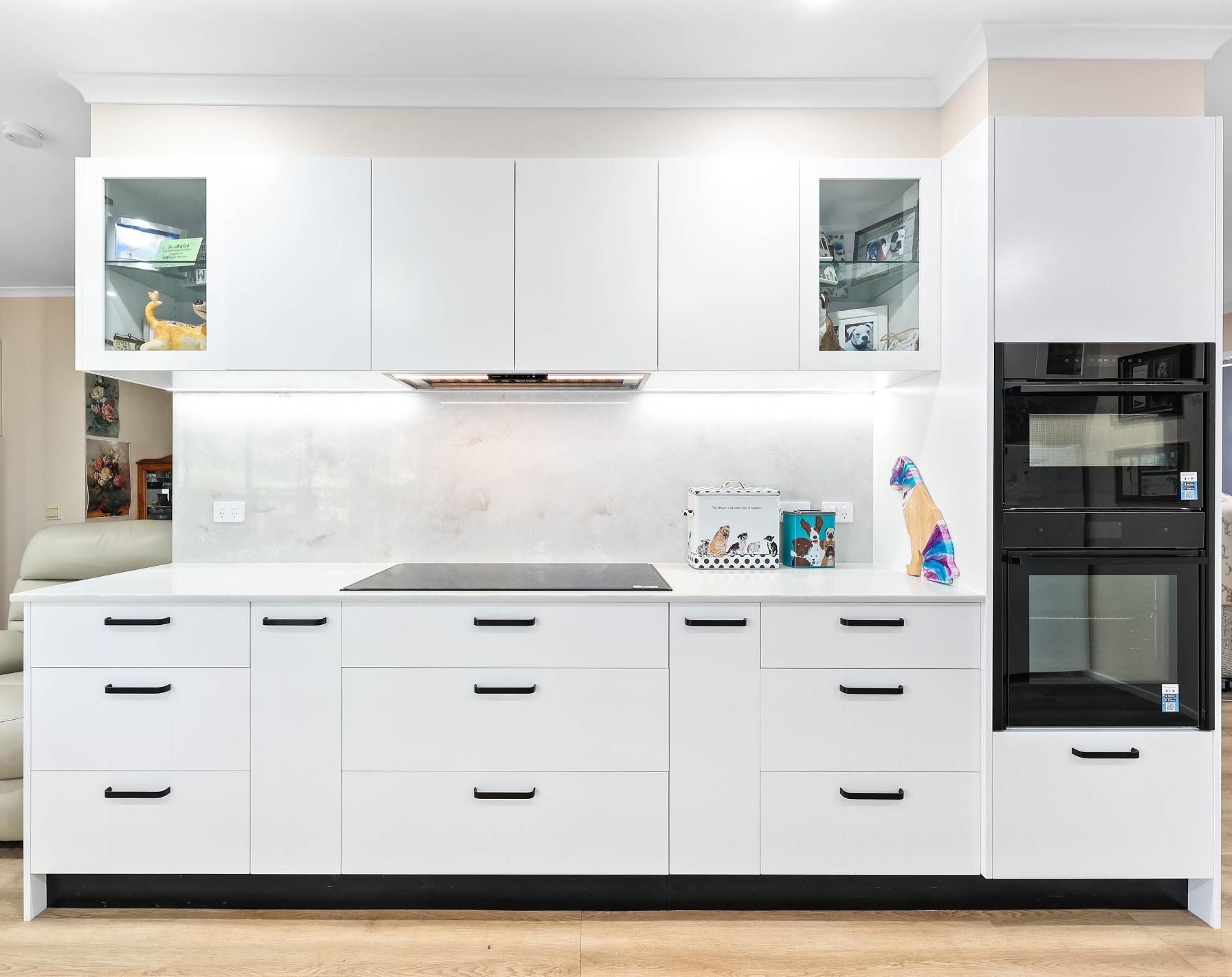 Modern White Kitchen with Built-In Appliances, Marble Backsplash, and Black Handles — Above & Beyond Interiors Custom Joinery in Bradbury, NSW