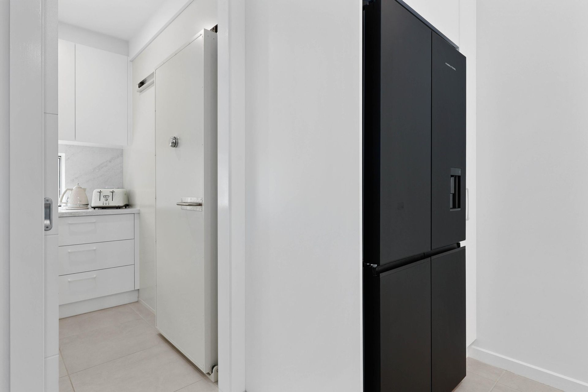 A Narrow Kitchen Hallway with A White Refrigerator, and A Black Refrigerator — Above & Beyond Interiors Custom Joinery in Currans Hill, NSW