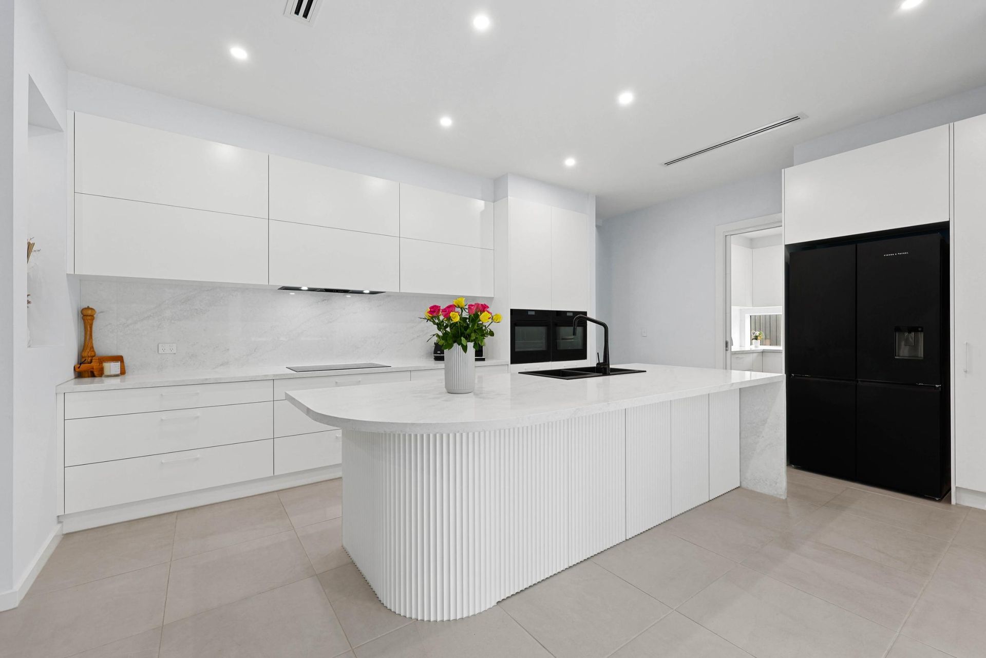 White Modern Kitchen with Island and Black Refrigerator — Above & Beyond Interiors Custom Joinery in Currans Hill, NSW
