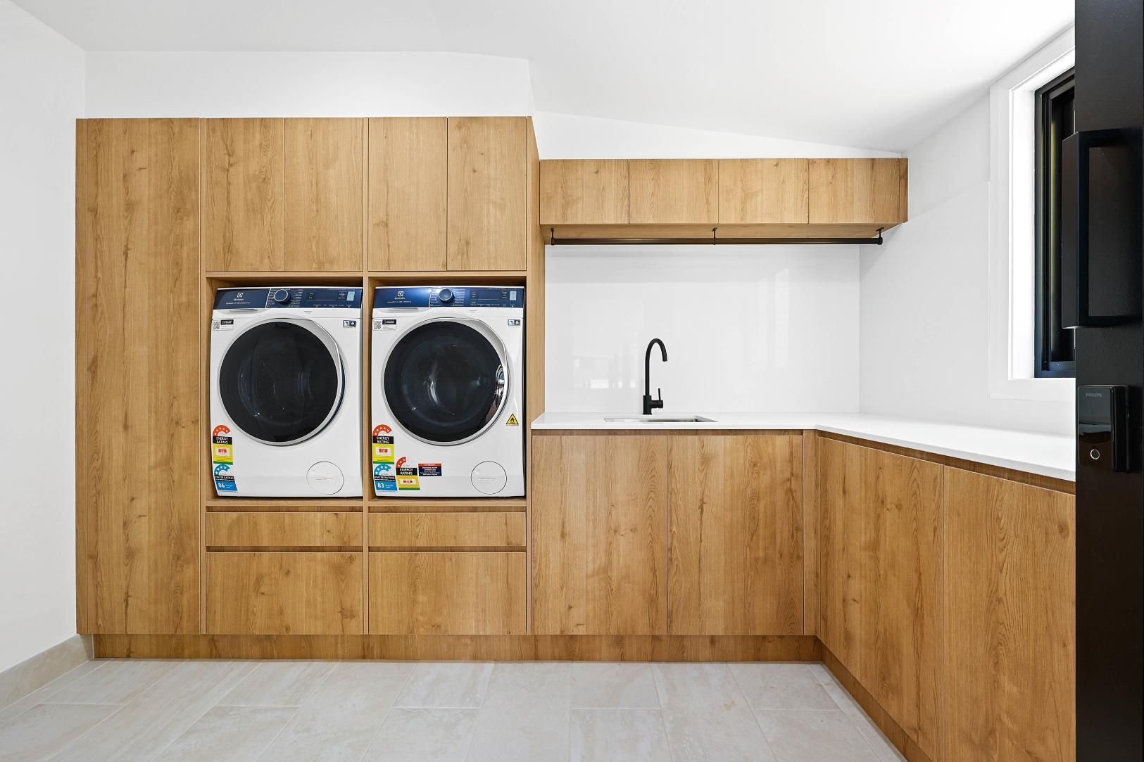 Laundry Room with Wood Grain Cabinets, Washer/dryer, Sink, and Window — Above & Beyond Interiors Custom Joinery in Abbortsbury, NSW