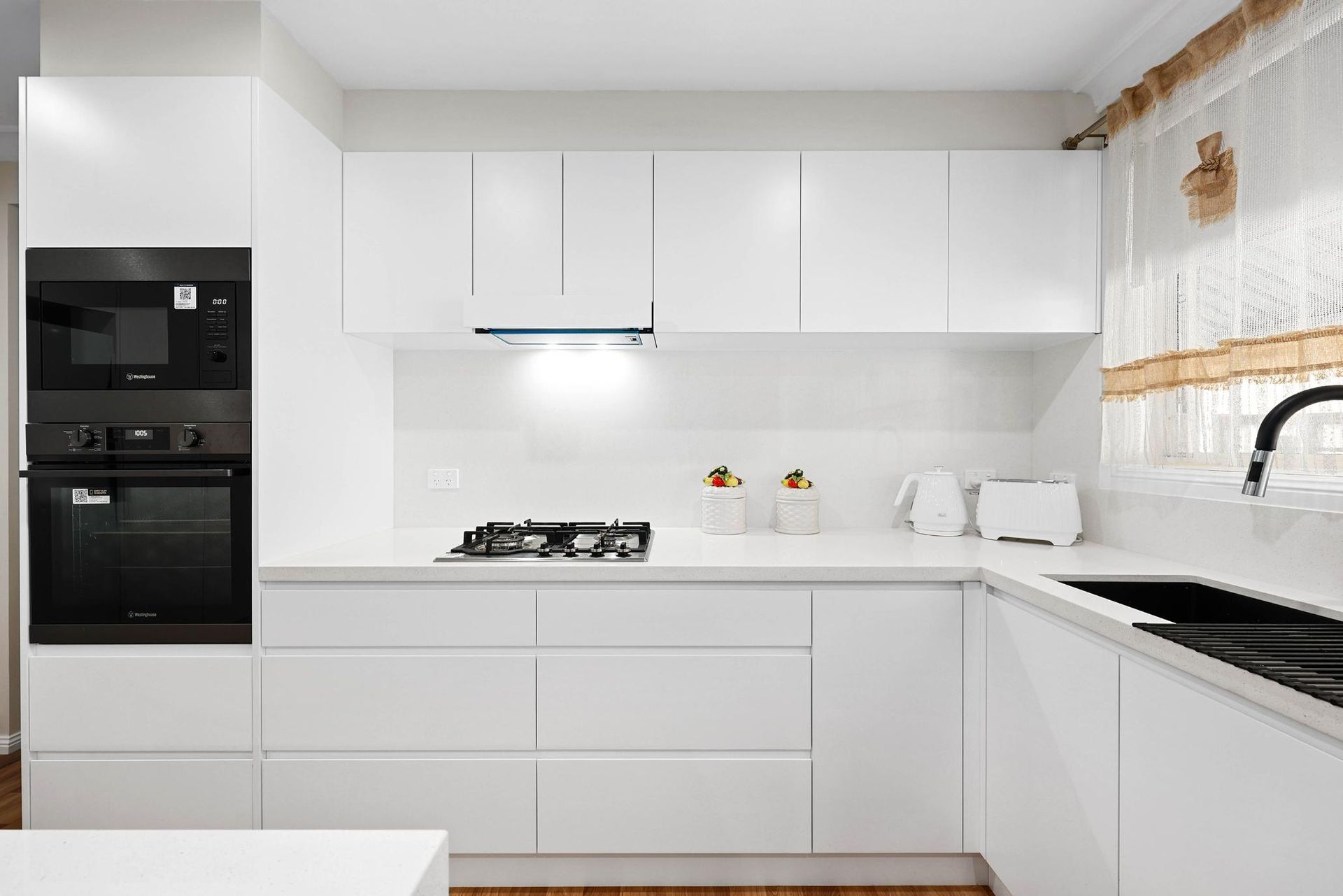 White Modern Kitchen with Black Appliances, Sink, and Stove — Above & Beyond Interiors Custom Joinery in Narellan Vale, NSW
