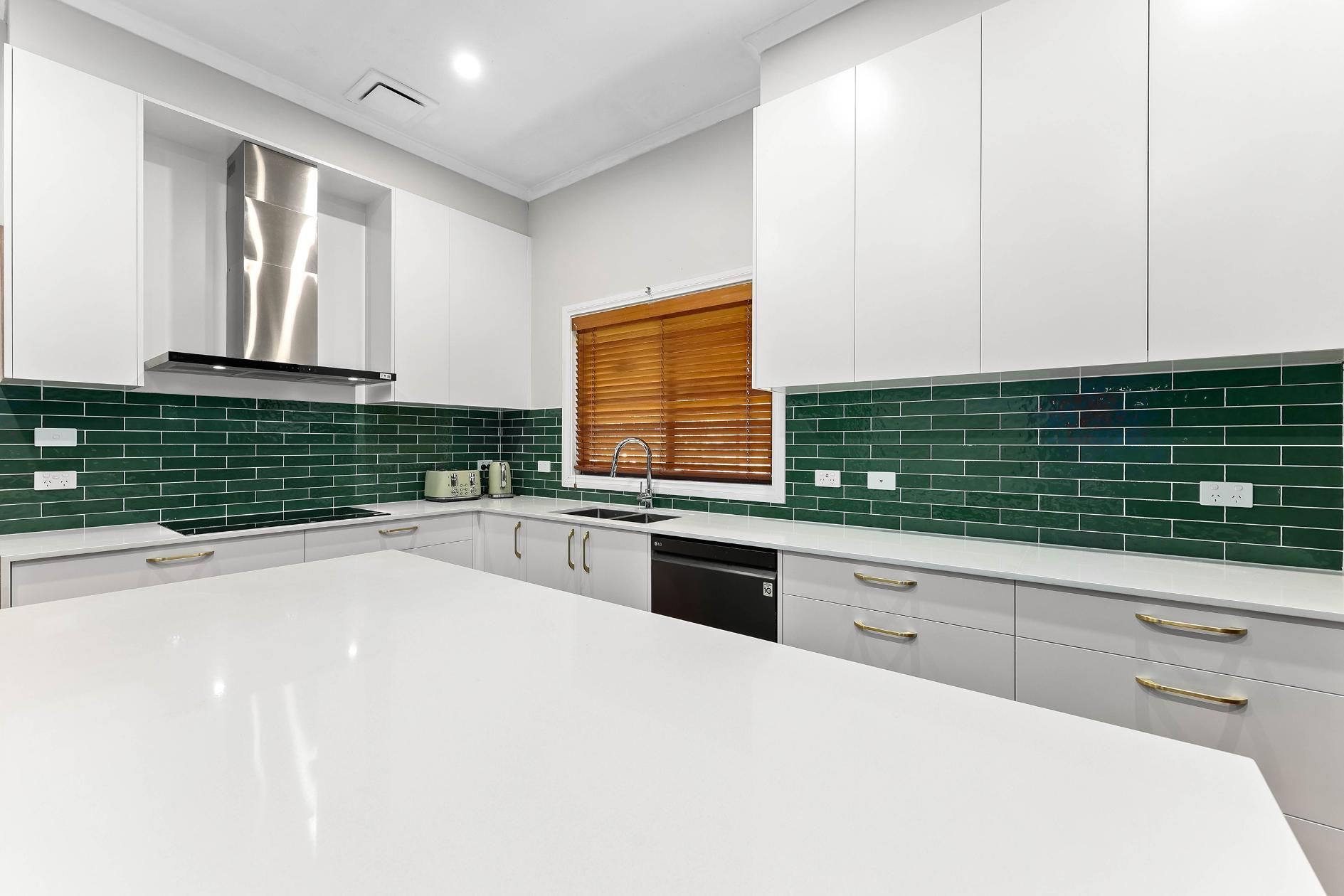 Modern Kitchen with White Cabinets, Green Tile Backsplash, and Large White Island — Above & Beyond Interiors Custom Joinery in Minto, NSW