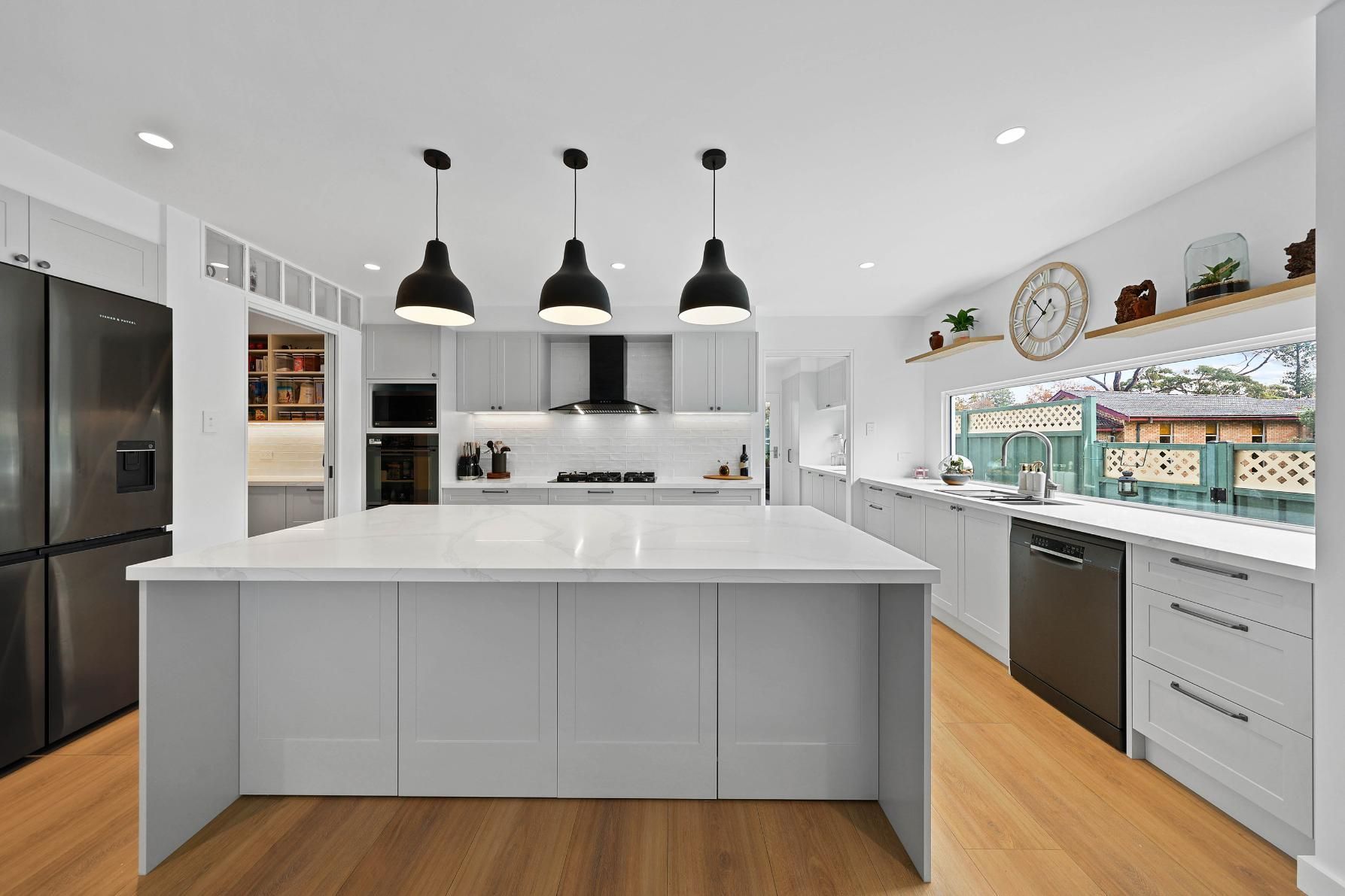 Modern Kitchen with Grey Cabinets, White Island, Black Appliances, and Pendant Lights — Above & Beyond Interiors Custom Joinery in Yowie Bay, NSW