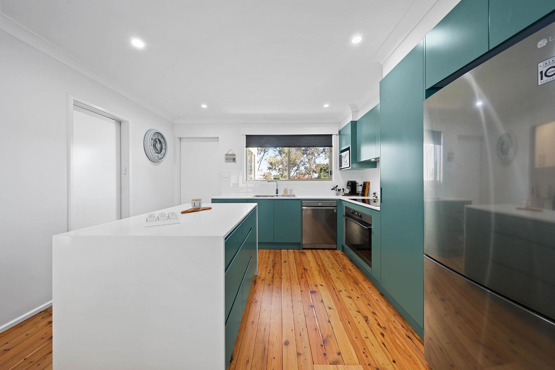Modern Kitchen with Teal Cabinets, White Island, Stainless Steel Appliances, and Wooden Floors — Above & Beyond Interiors Custom Joinery in Bradbury, NSW