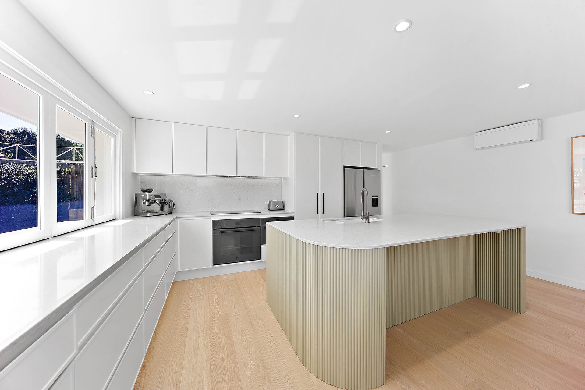 Modern white kitchen with island and cabinetry; light wood floors, neutral color scheme — Above & Beyond Interiors Custom Joinery in Bellambi, NSW