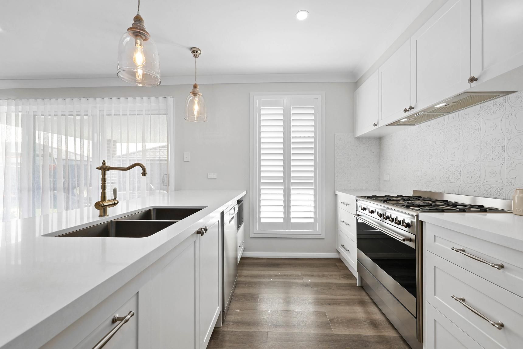 Bright White Kitchen with A Large Island, Brass Faucet, and Stainless Steel Appliances — Above & Beyond Interiors Custom Joinery in Thirlmere, NSW