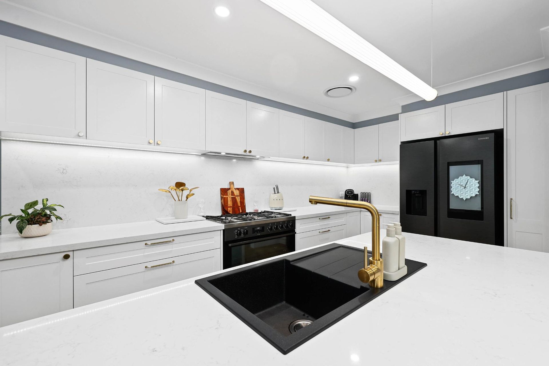 Modern White Kitchen with Black Accents, Gold Faucet, and Large Refrigerator — Above & Beyond Interiors Custom Joinery in Harrington Park, NSW