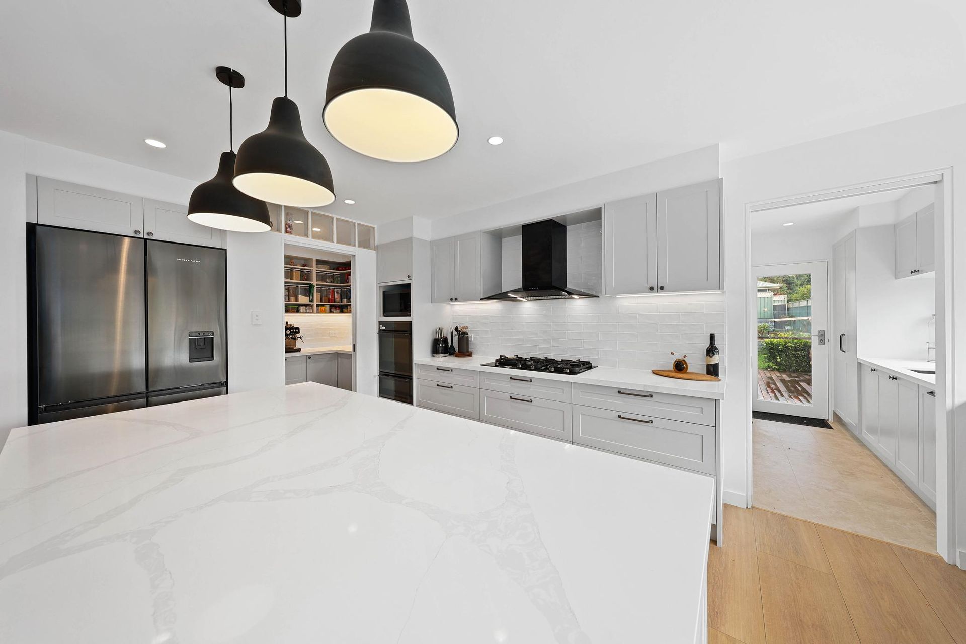 Modern Kitchen with A White Countertop Island, Grey Cabinets, Black Pendant Lights, and Stainless Steel Appliances — Above & Beyond Interiors Custom Joinery in Yowie Bay, NSW