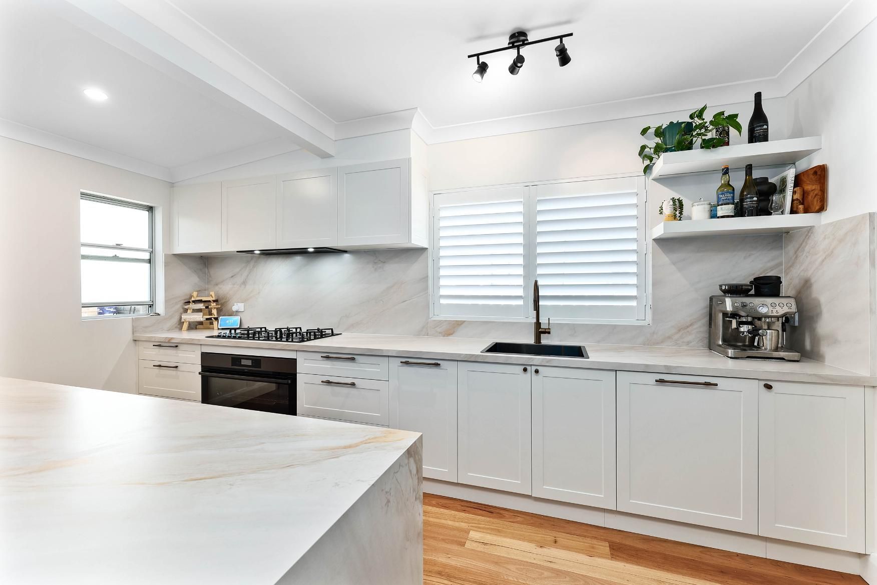 White Kitchen with Marble Countertops and Cabinets, Shutters, and A Coffee Machine — Above & Beyond Interiors Custom Joinery in Bellambi, NSW