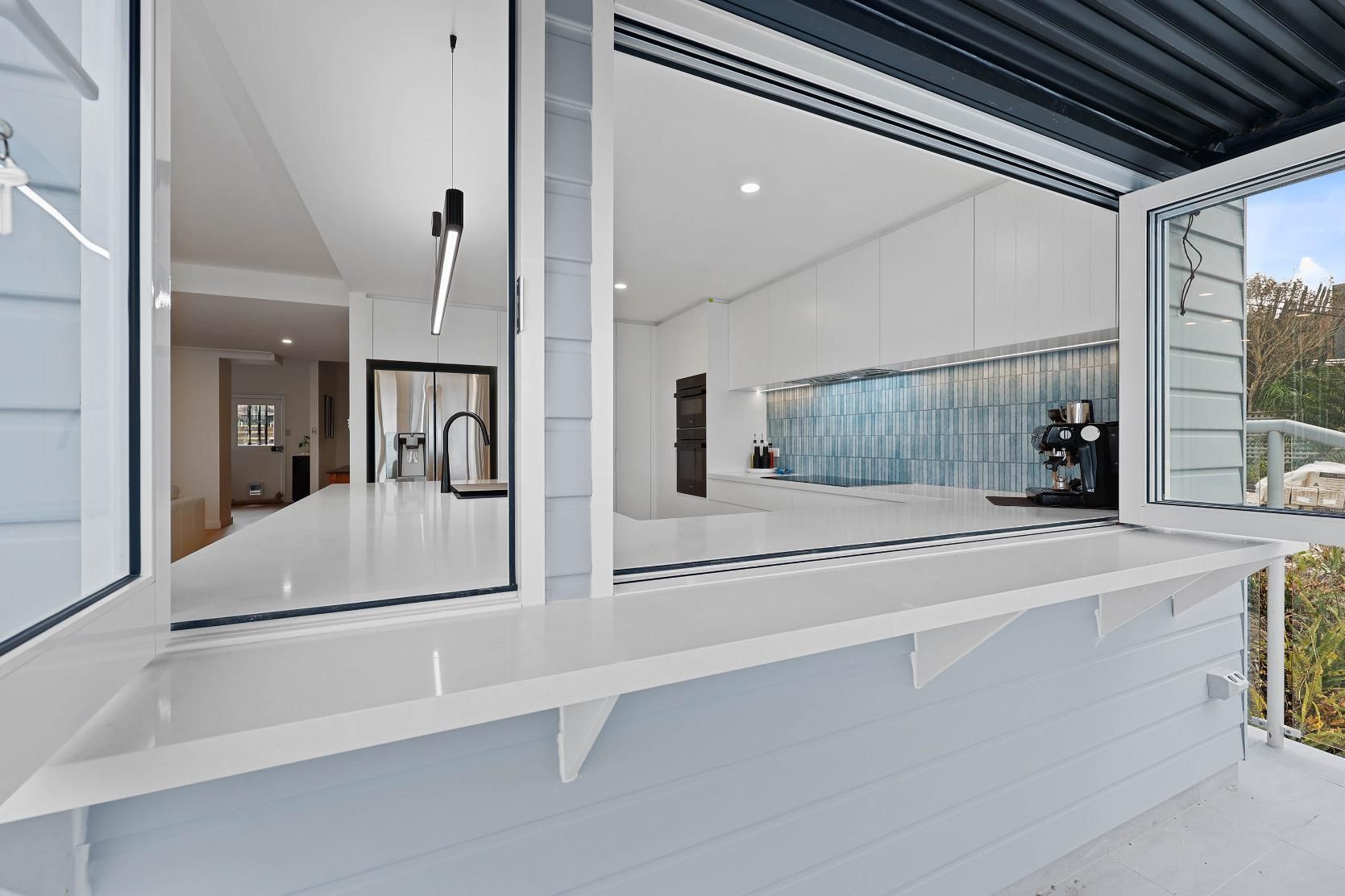 Bright Modern Kitchen with A Pass-Through Window to An Outdoor Bar Area. White and Light Blue Colors Dominate — Above & Beyond Interiors Custom Joinery in North Curl Curl, NSW