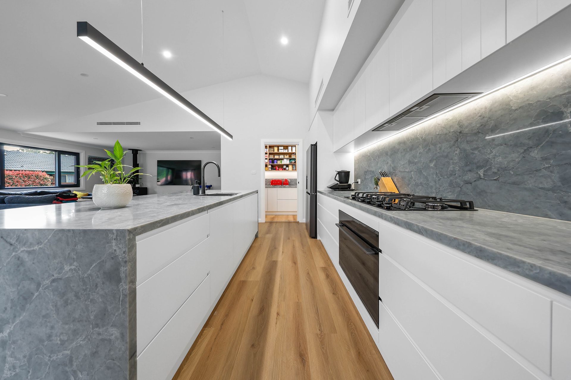 Modern kitchen with white cabinets, marble countertops, and wood floors — Above & Beyond Interiors Custom Joinery in Bellambi, NSW