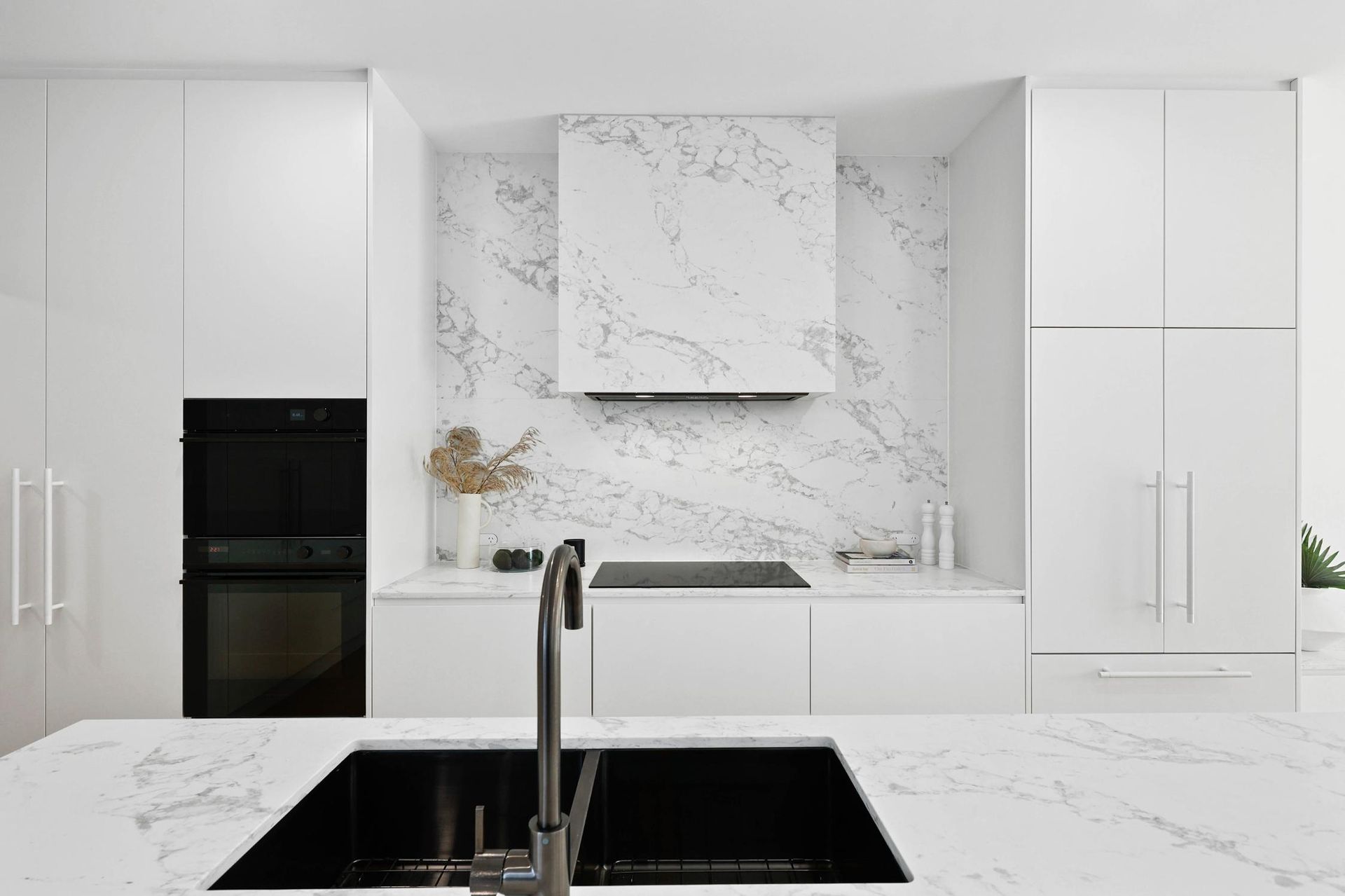 Modern White Kitchen with Black Sink, Oven, and Marble Backsplash — Above & Beyond Interiors Custom Joinery in Thirroul, NSW