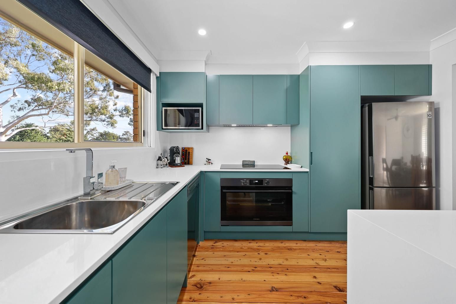 Modern Teal Kitchen with Stainless Steel Appliances and Wooden Floor — Above & Beyond Interiors Custom Joinery in Bradbury, NSW