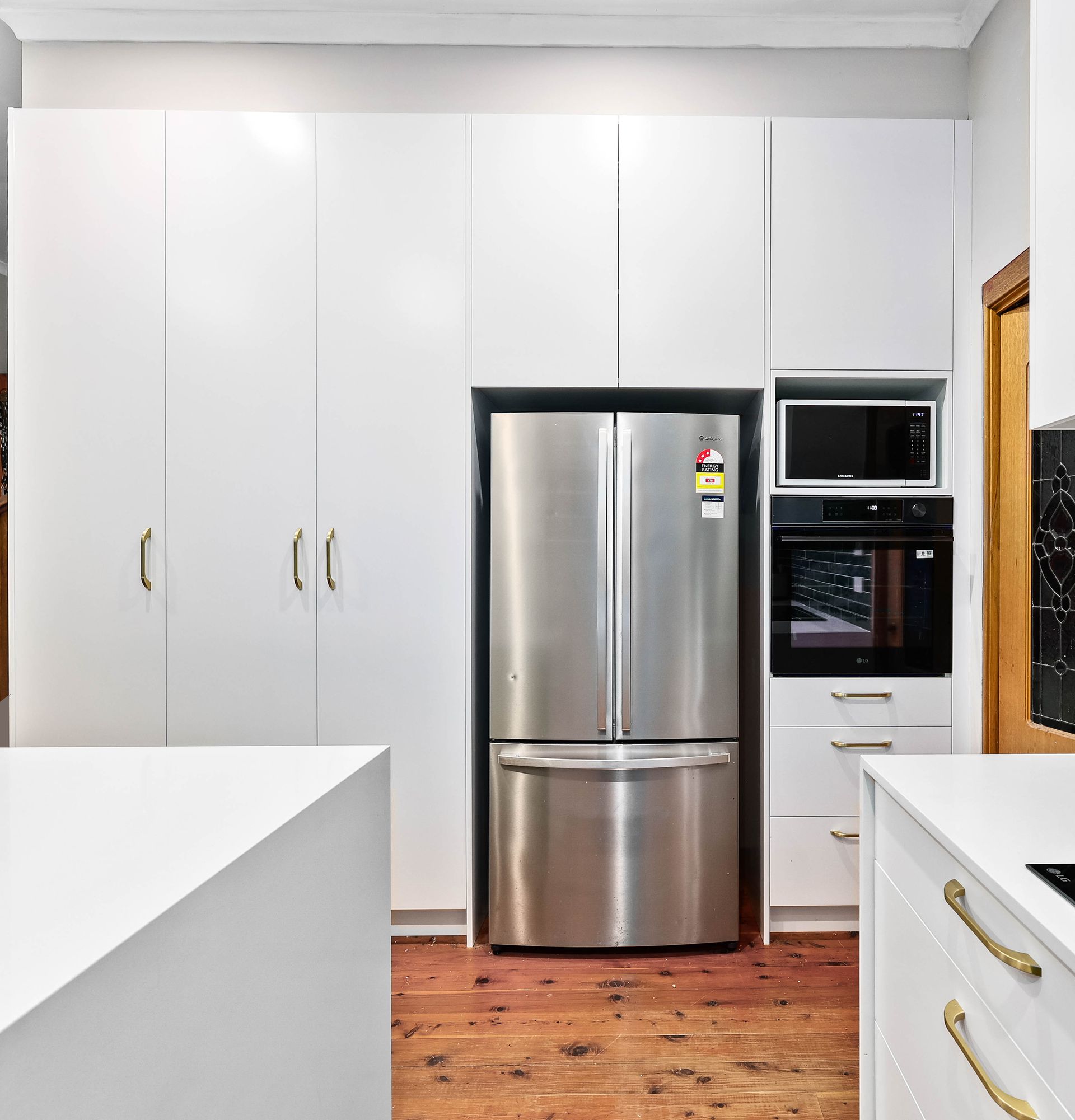 Modern Kitchen with White Cabinets and Stainless Steel Refrigerator — Above & Beyond Interiors in Smeaton Grange, NSW