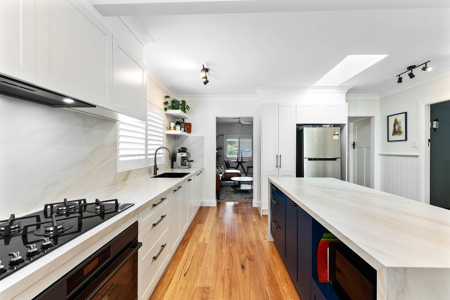 Modern Kitchen with White Cabinetry, Navy Island, Wood Floors, and Stainless Steel Appliances — Above & Beyond Interiors Custom Joinery in Bellambi, NSW