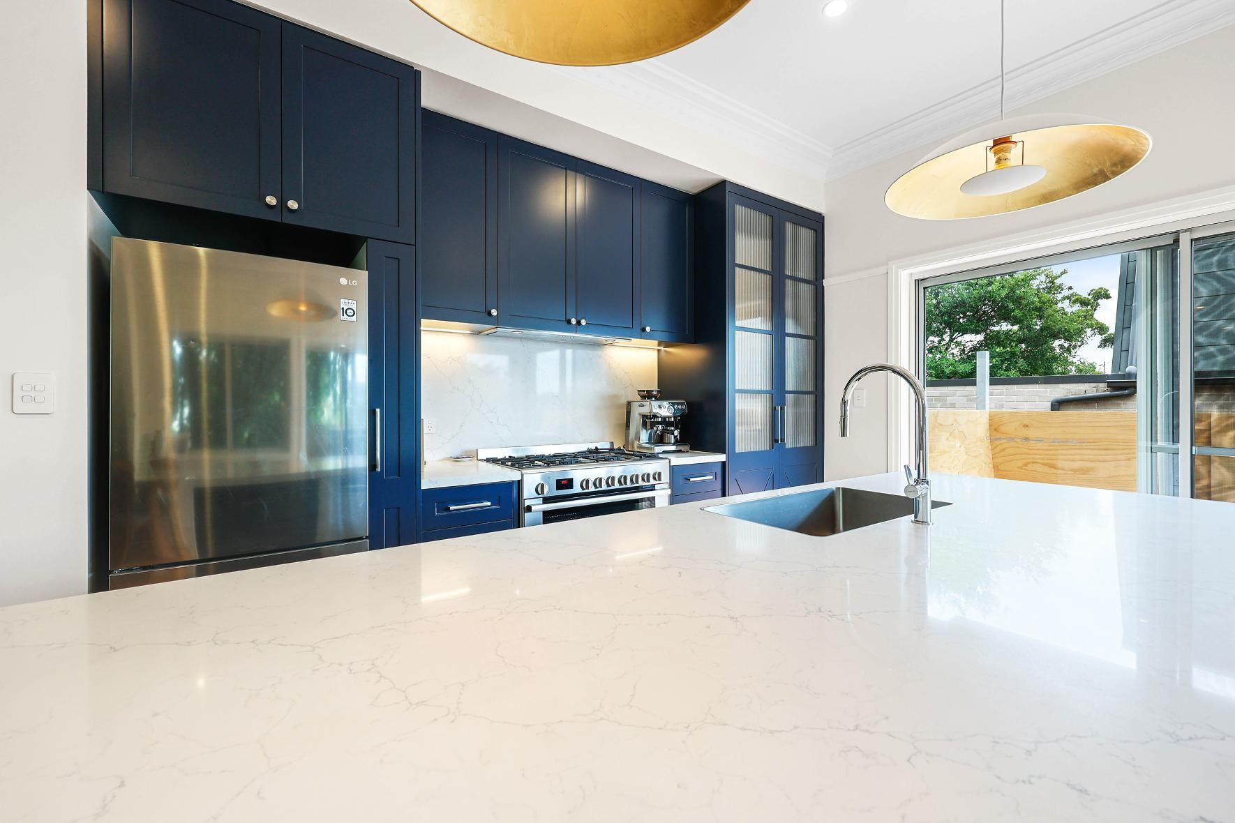 Modern Kitchen with Blue Cabinets, Stainless Steel Appliances, White Countertop, and Gold Light Fixtures — Above & Beyond Interiors Custom Joinery in Lilyfield, NSW