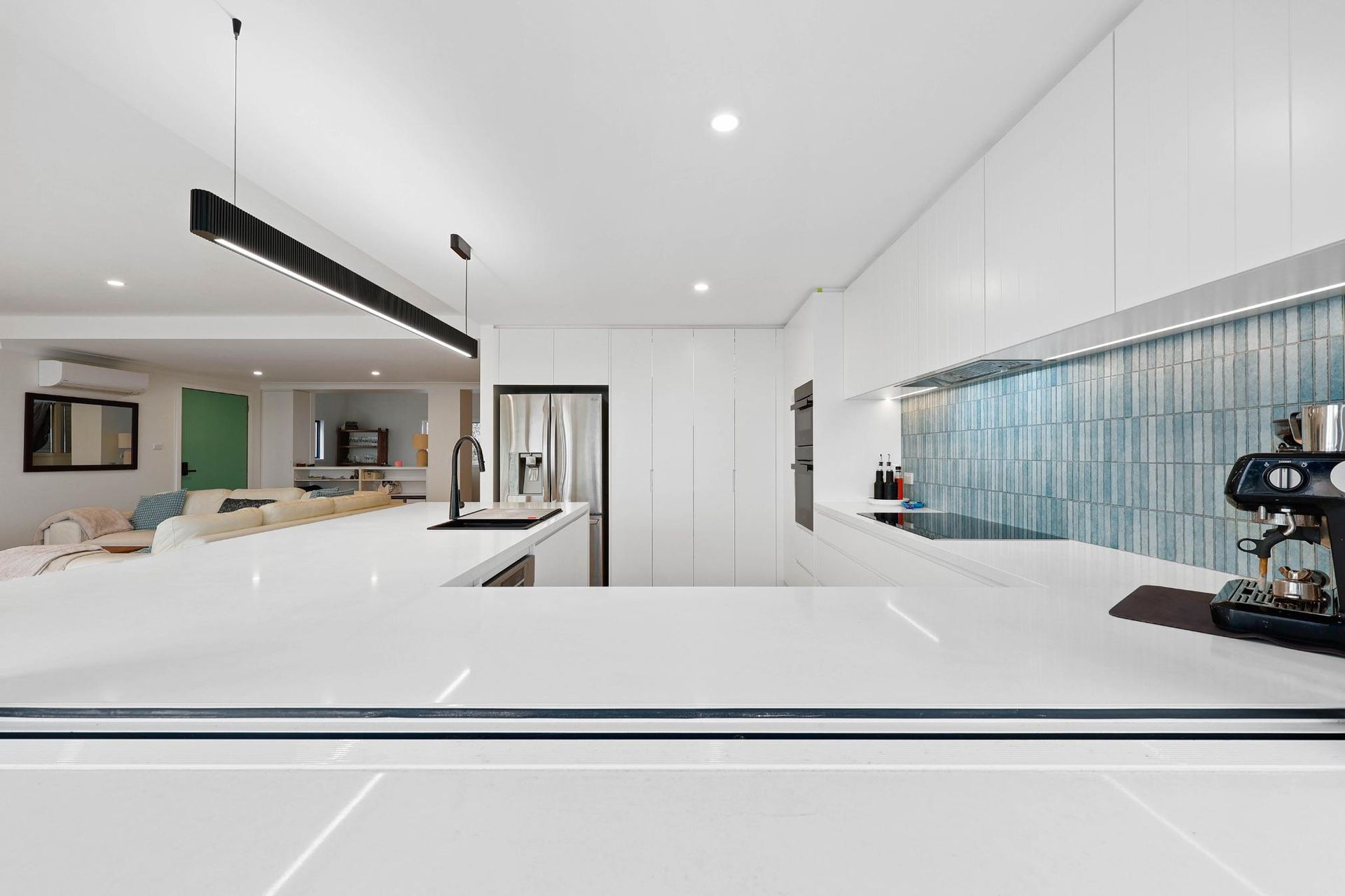 Modern White Kitchen with A Large Island, Blue Backsplash, and Espresso Machine — Above & Beyond Interiors Custom Joinery in North Curl Curl, NSW