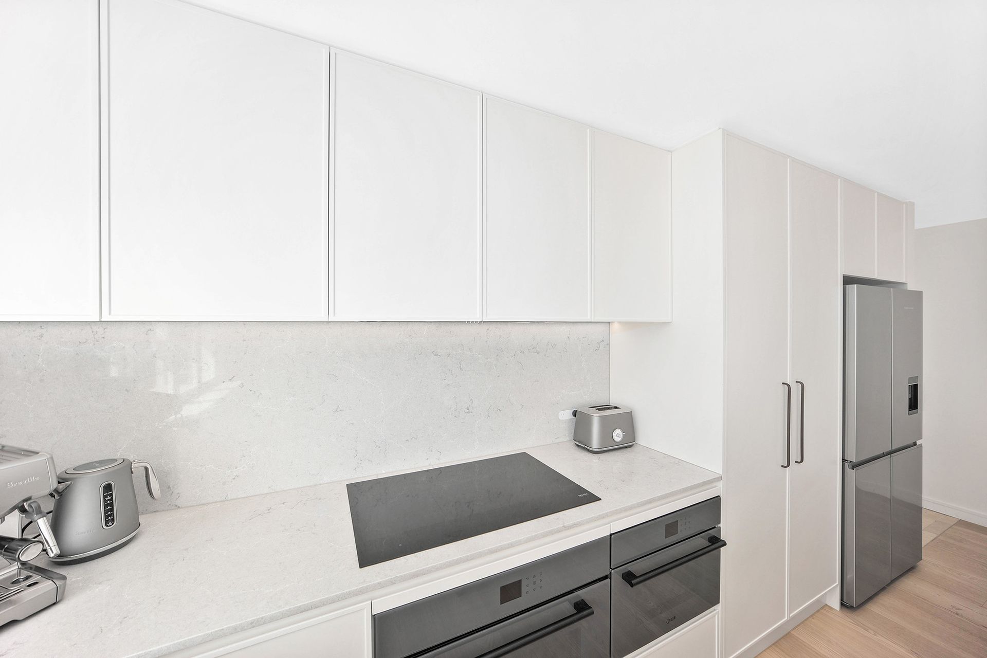 White modern kitchen with countertop, cabinets, appliances, and fridge — Above & Beyond Interiors Custom Joinery in Bellambi, NSW