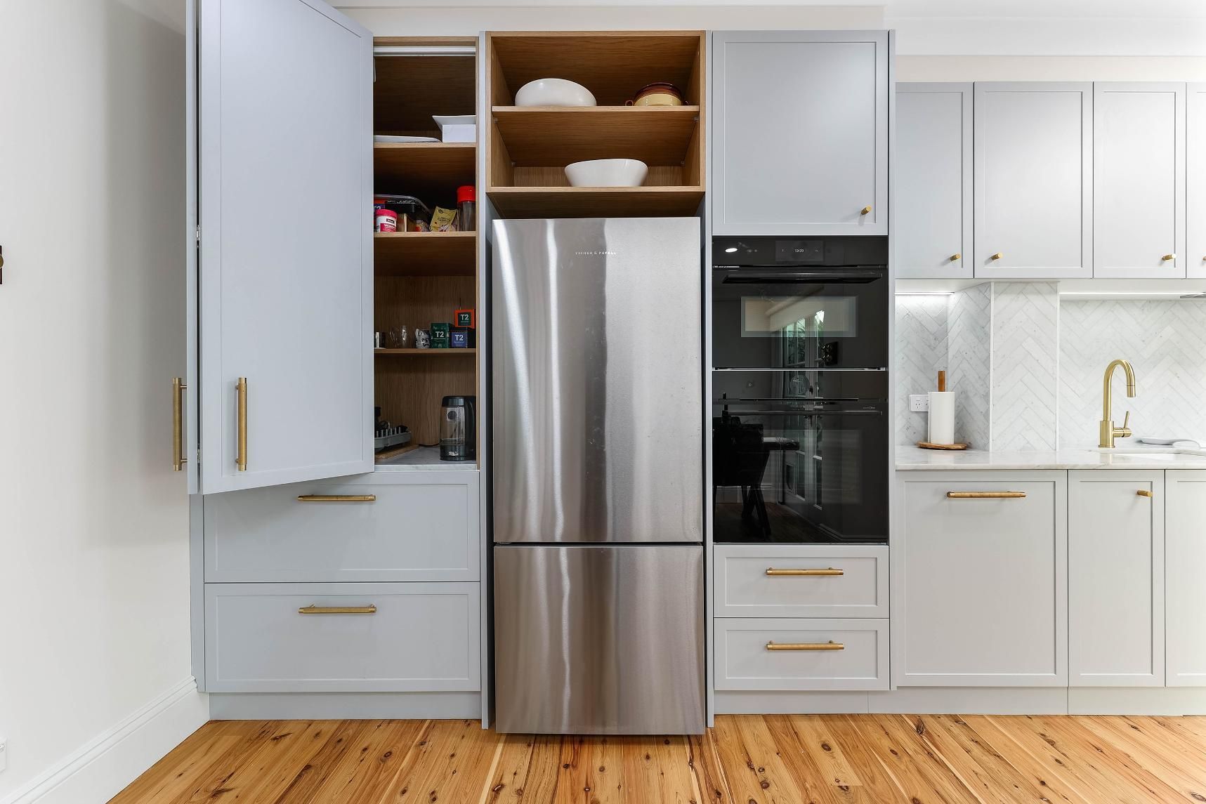 Light Blue Kitchen Cabinetry with Stainless Steel Fridge, Oven, and Pantry on Wooden Floor — Above & Beyond Interiors Custom Joinery in Erskineville, NSW