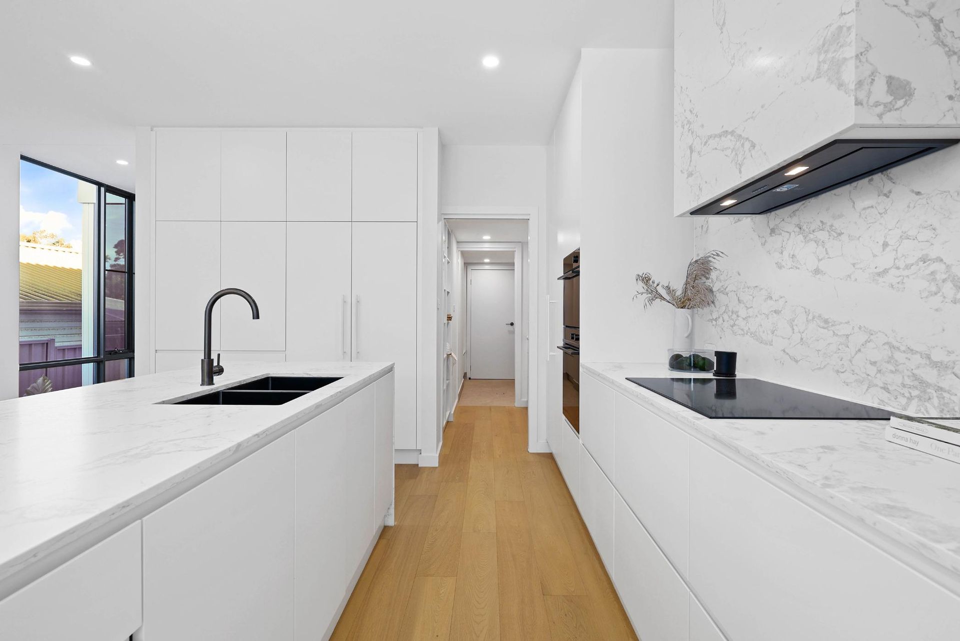 Modern White Kitchen with Island and Long Counter, Wood Floors, Stainless Steel Appliances — Above & Beyond Interiors Custom Joinery in Thirroul, NSW