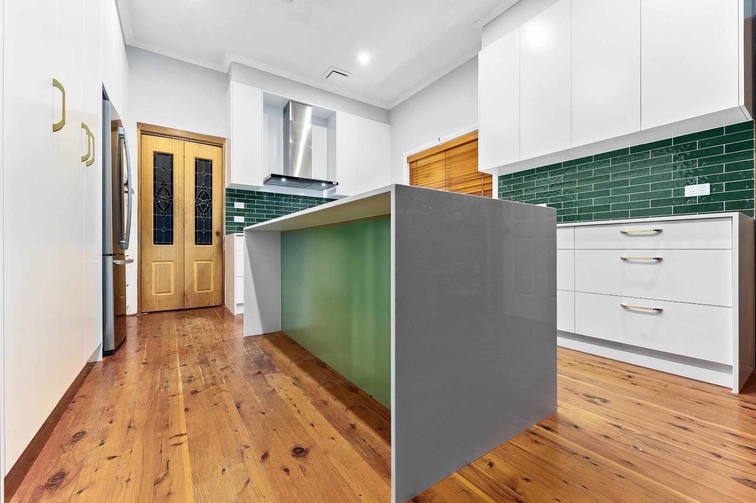 Modern Kitchen with A Grey Island and Green Accents, Hardwood Floors, and White Cabinets — Above & Beyond Interiors Custom Joinery in Minto, NSW
