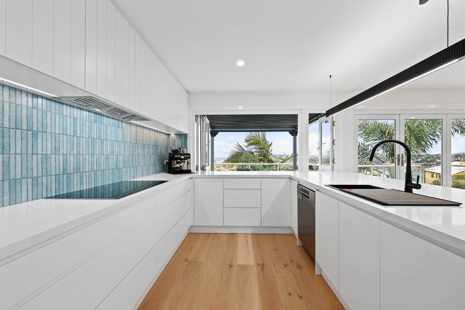 Modern White Kitchen with Blue Tile Backsplash, Light Wood Floors, and Open View — Above & Beyond Interiors Custom Joinery in North Curl Curl, NSW