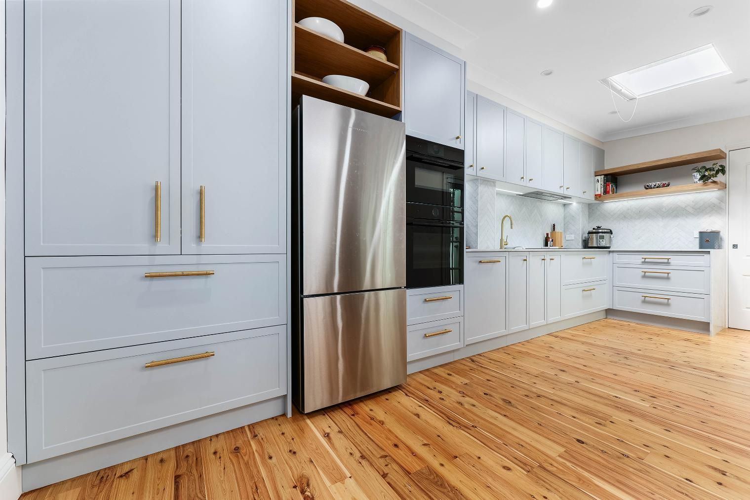 Light Blue Kitchen with Wood Floors and Stainless Steel Refrigerator and Oven — Above & Beyond Interiors Custom Joinery in Erskineville, NSW