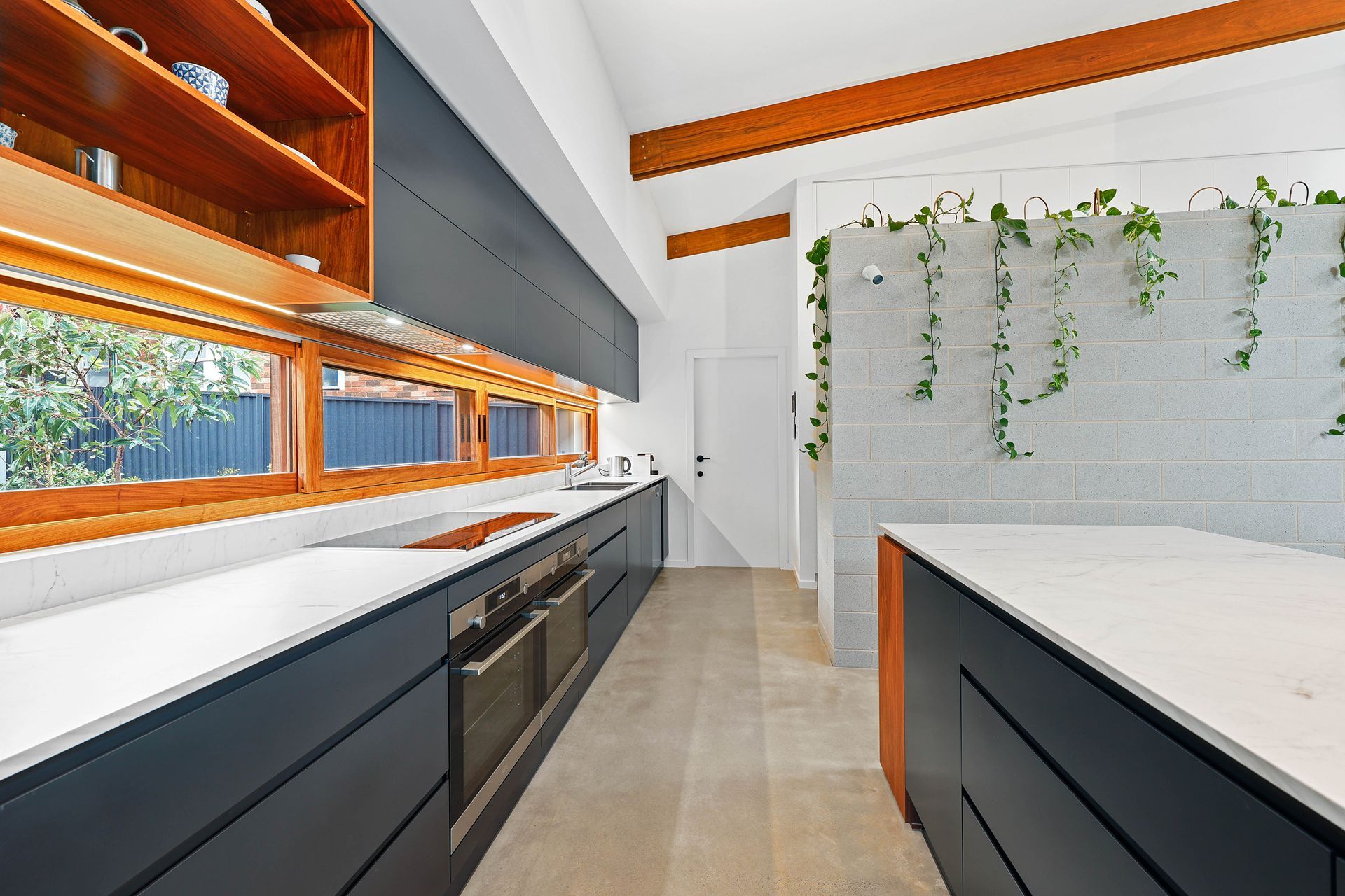 Modern kitchen with grey cabinets, wooden accents, and a white countertop, island with plants — Above & Beyond Interiors Custom Joinery in Bellambi, NSW
