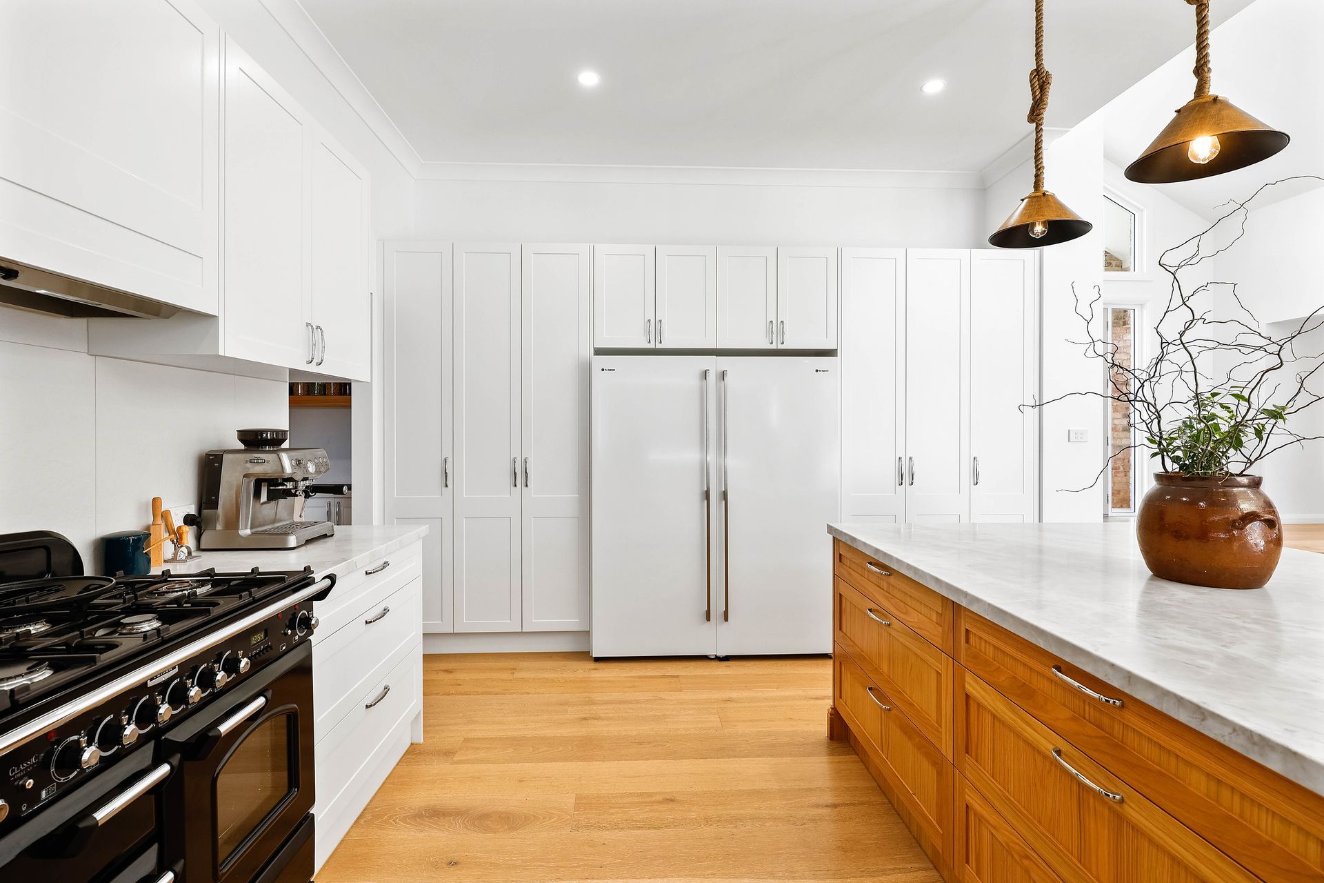 Bright white kitchen with wood island, white cabinets, and black range — Above & Beyond Interiors Custom Joinery in Bradbury, NSW