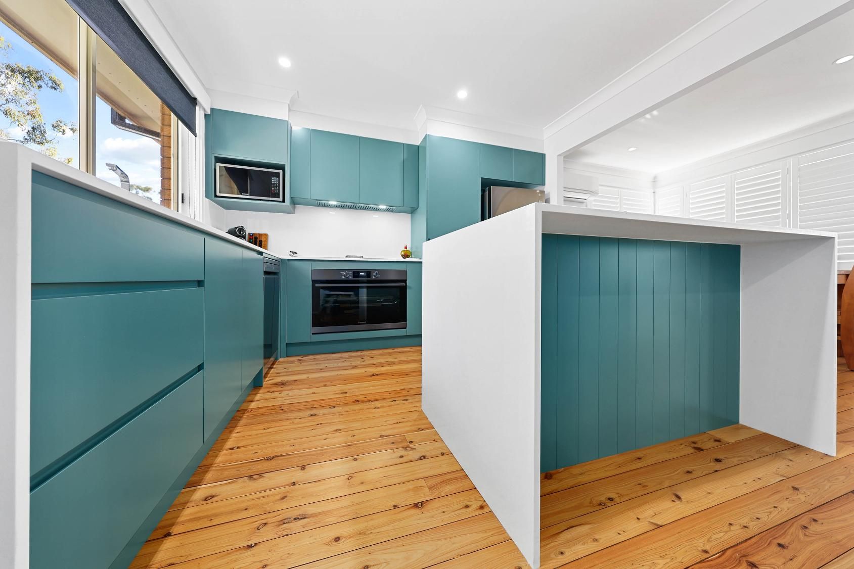 Teal and White Kitchen with Wood Floors. Island, Cabinets, and Appliances — Above & Beyond Interiors Custom Joinery in Bradbury, NSW