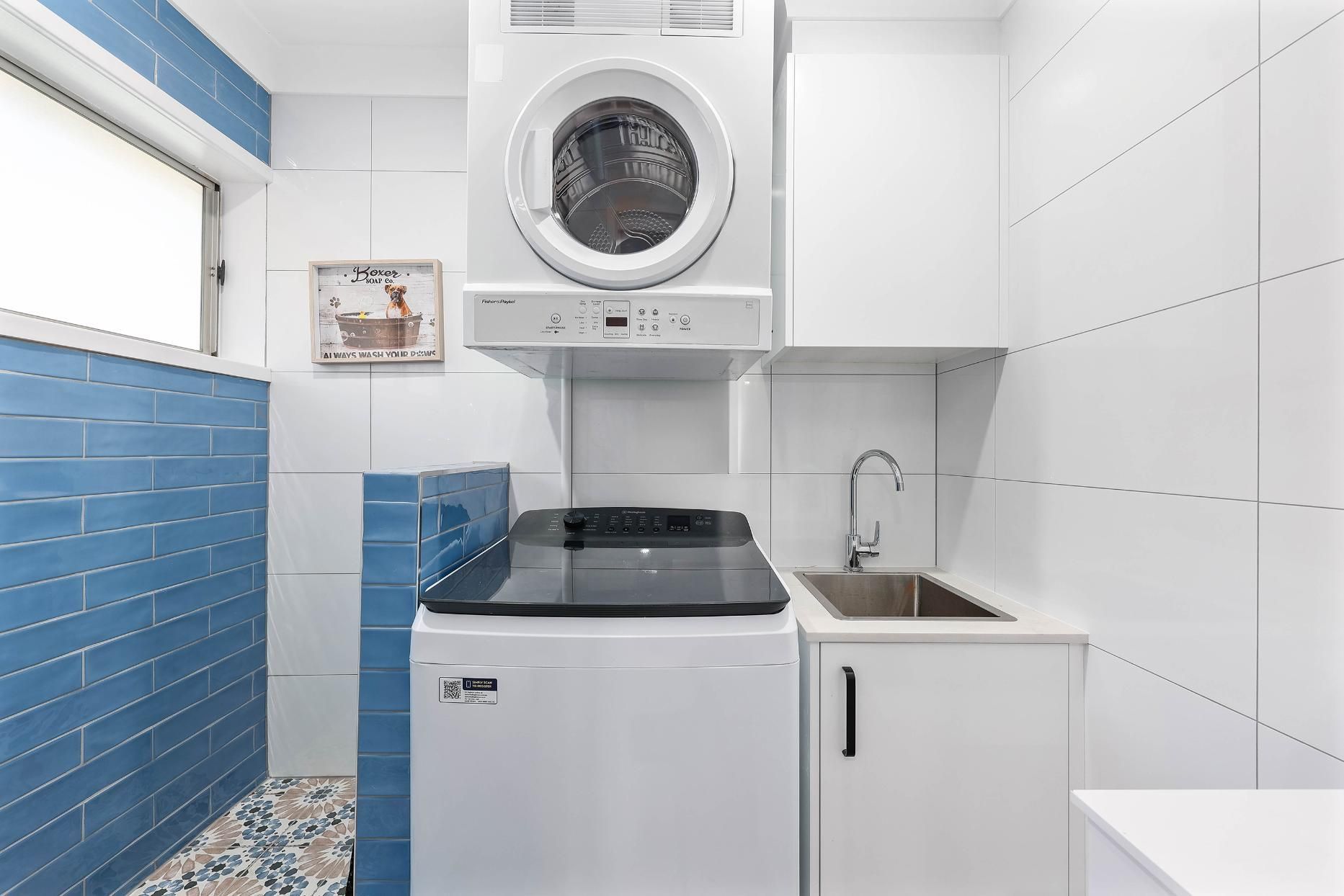 Laundry Room with A Stacked Washer and Dryer, a Sink, and Blue and White Tile — Above & Beyond Interiors Custom Joinery in Bradbury, NSW