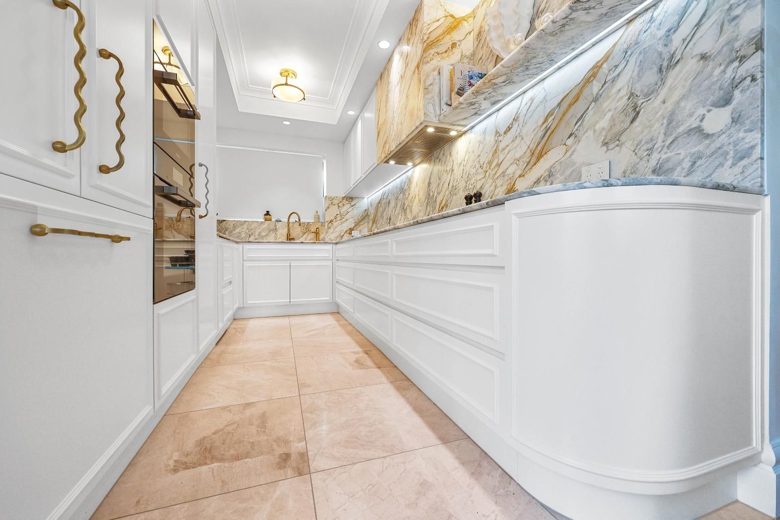 Elegant White Kitchen with Marble Backsplash, Gold Accents, and A Curved Cabinet — Above & Beyond Interiors Custom Joinery in Double Bay, NSW