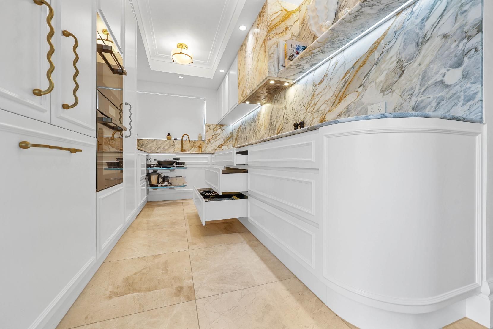 Elegant White Kitchen with Marble Backsplash, Open Drawers, and Brass Hardware — Above & Beyond Interiors Custom Joinery in Double Bay, NSW