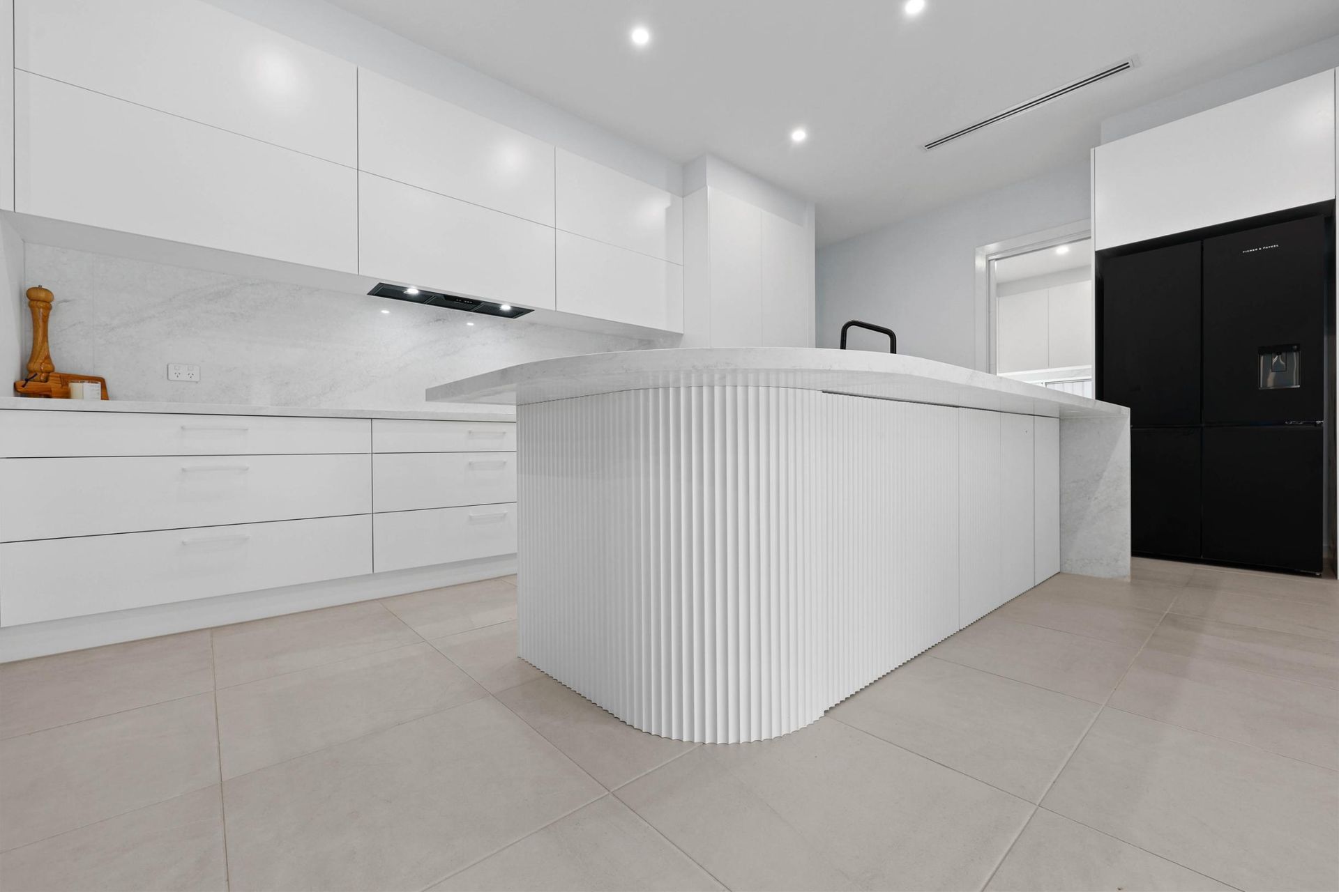 Modern White Kitchen with Curved Island, Black Fridge, and Marble Backsplash — Above & Beyond Interiors Custom Joinery in Currans Hill, NSW