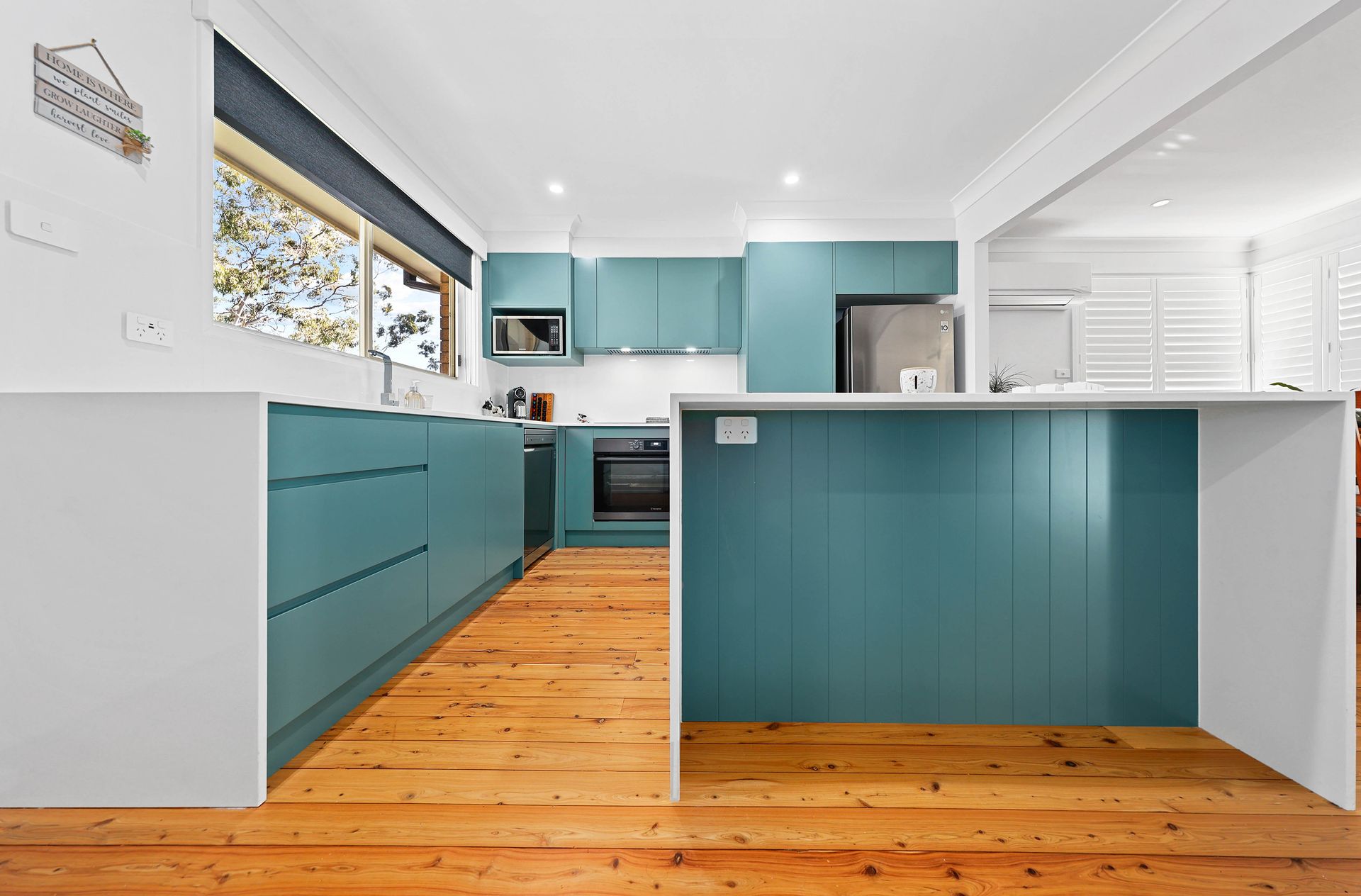 Teal kitchen with wood floors, white countertops and appliances — Above & Beyond Interiors Custom Joinery in Bellambi, NSW