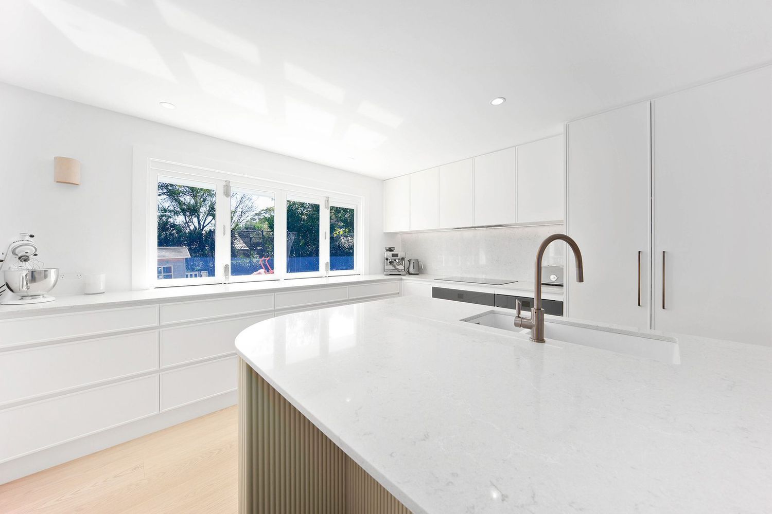 Bright White Modern Kitchen With Curved Island — Above & Beyond Interiors in Smeaton Grange, NSW