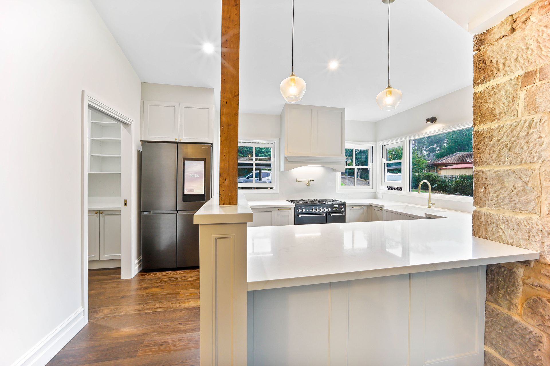 Modern kitchen with white cabinets, island, and exposed brick wall — Above & Beyond Interiors Custom Joinery in Bradbury, NSW