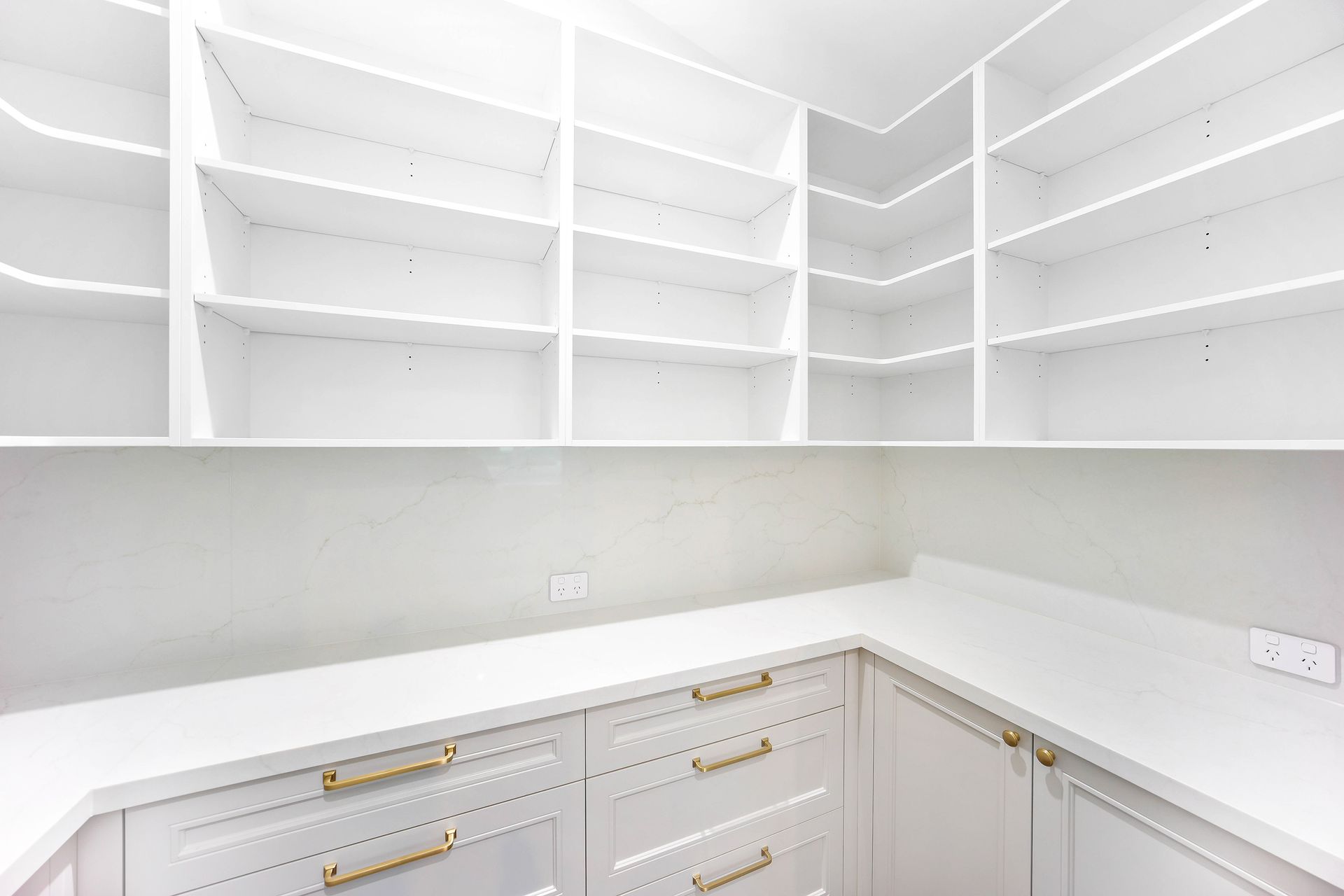 White pantry with built-in shelves and cabinets. Features a countertop and gold hardware — Above & Beyond Interiors Custom Joinery in Bradbury, NSW