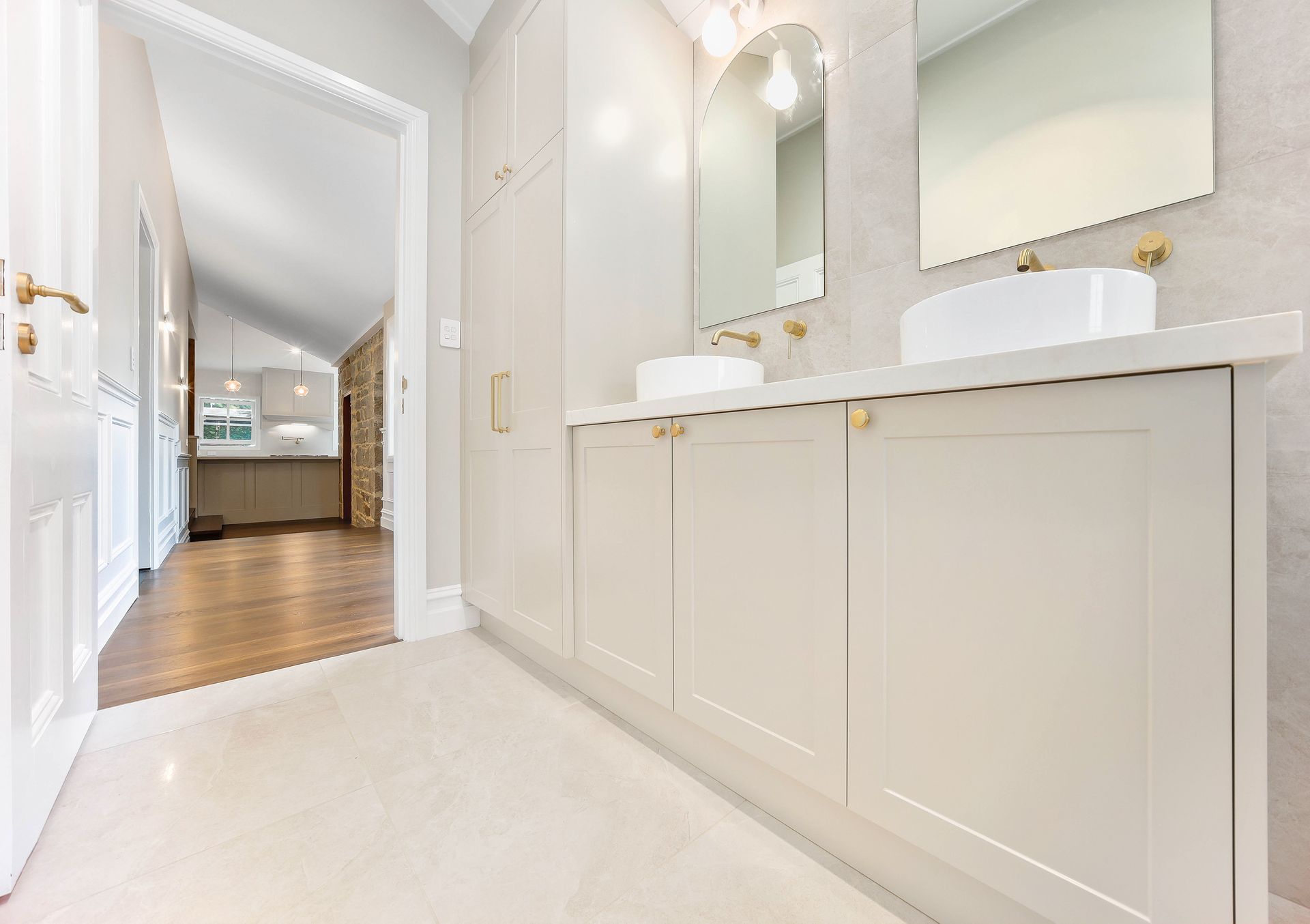 Bathroom with double vanity and arch mirror, neutral tones, gold fixtures — Above & Beyond Interiors Custom Joinery in Bradbury, NSW