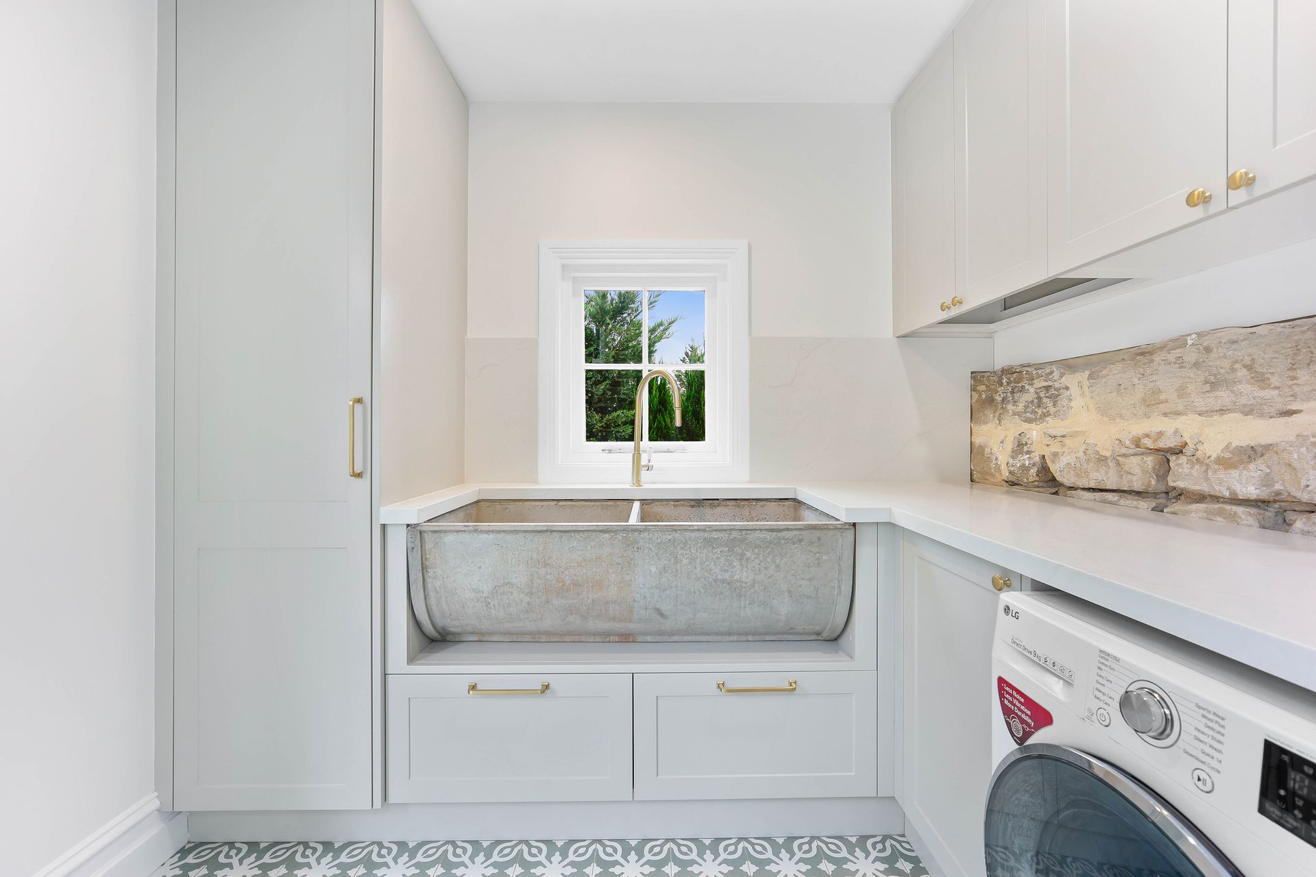 Laundry room with white cabinets, a large sink, washing machine, and a window — Above & Beyond Interiors Custom Joinery in Bradbury, NSW