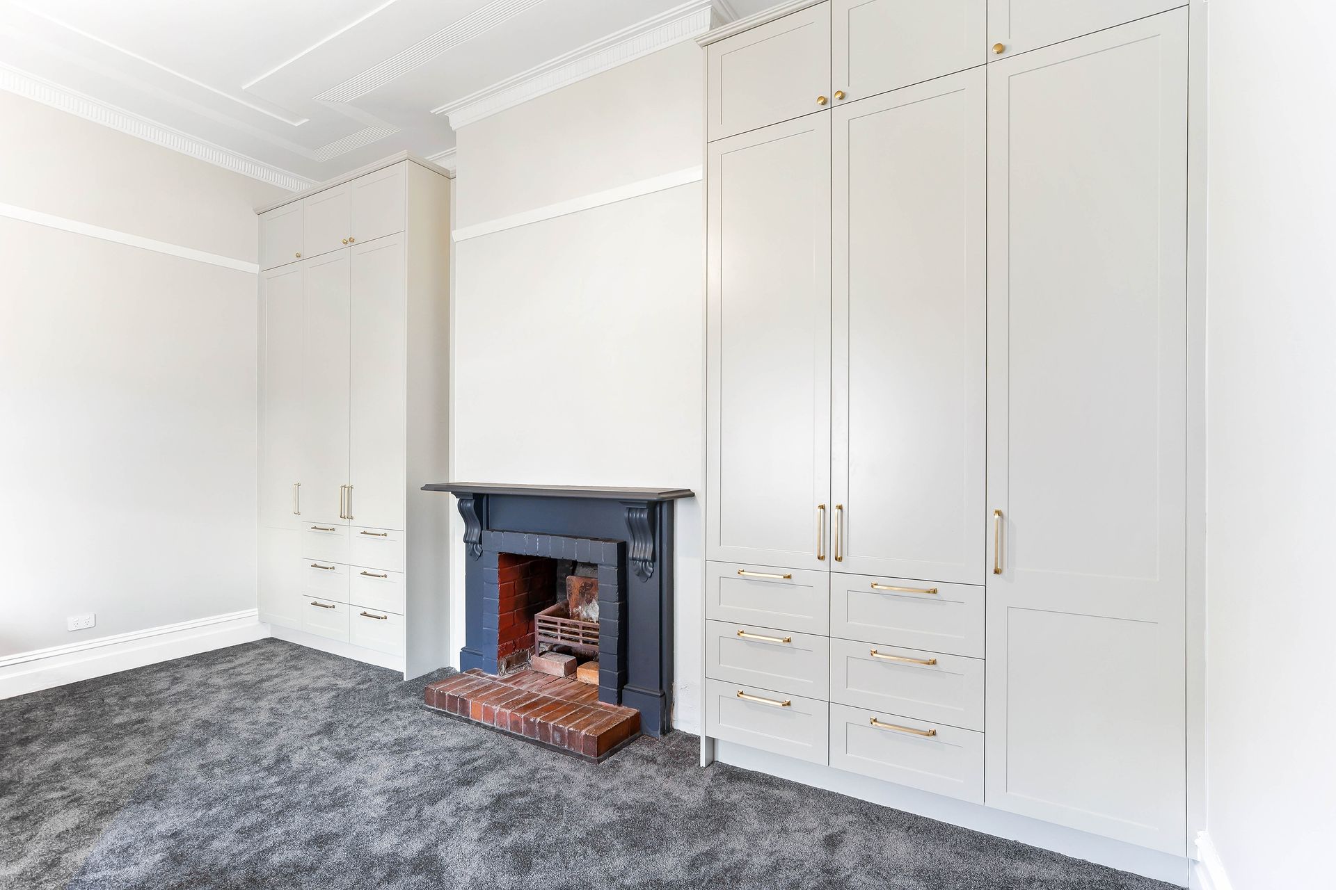 Bedroom with built-in cream-colored wardrobes, a fireplace, and grey carpet — Above & Beyond Interiors Custom Joinery in Bradbury, NSW