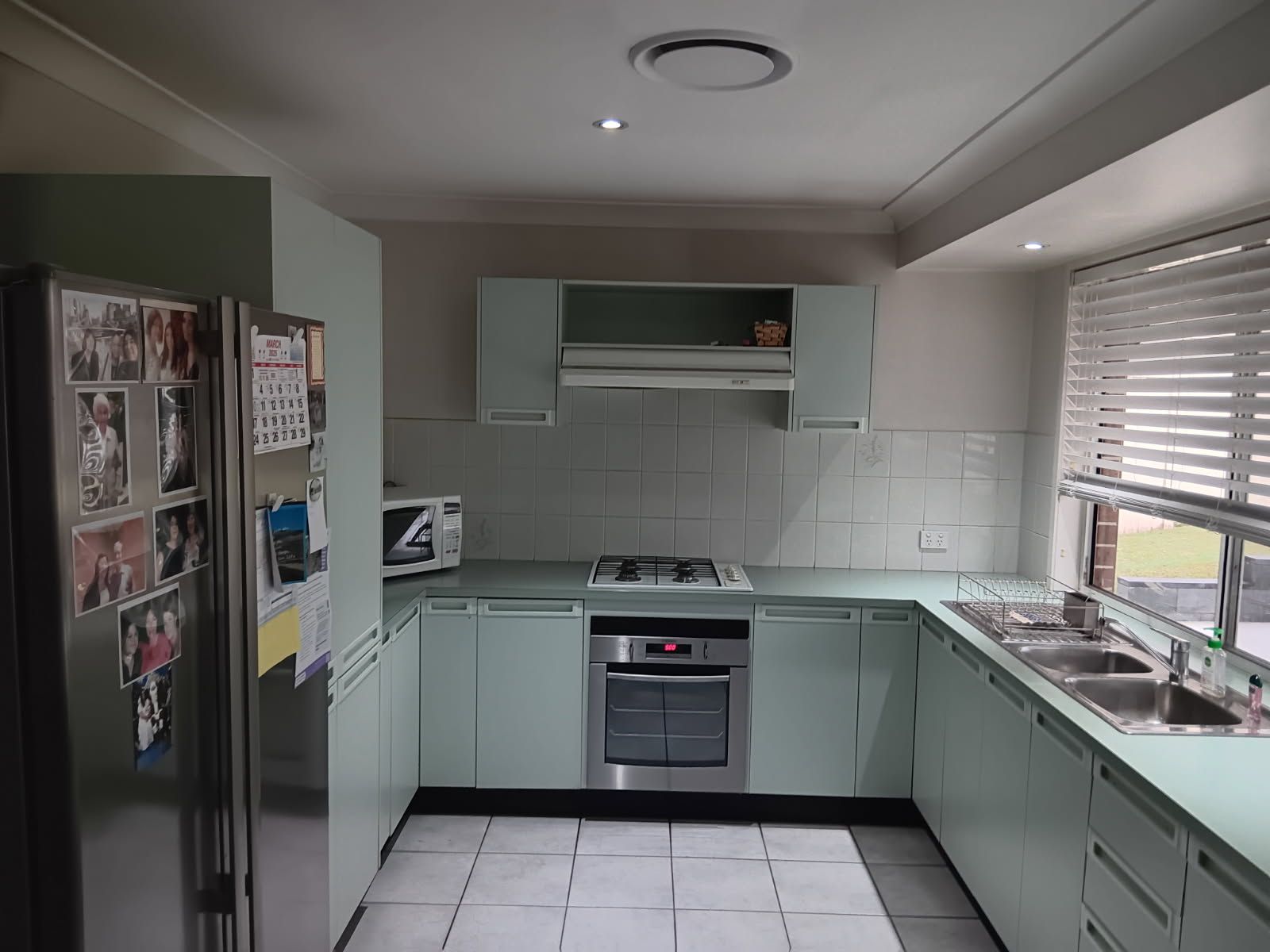 Kitchen with white cabinets, appliances, and dark blue wall, wooden floor, small table and small tv — Above & Beyond Interiors in Smeaton Grange, NSW