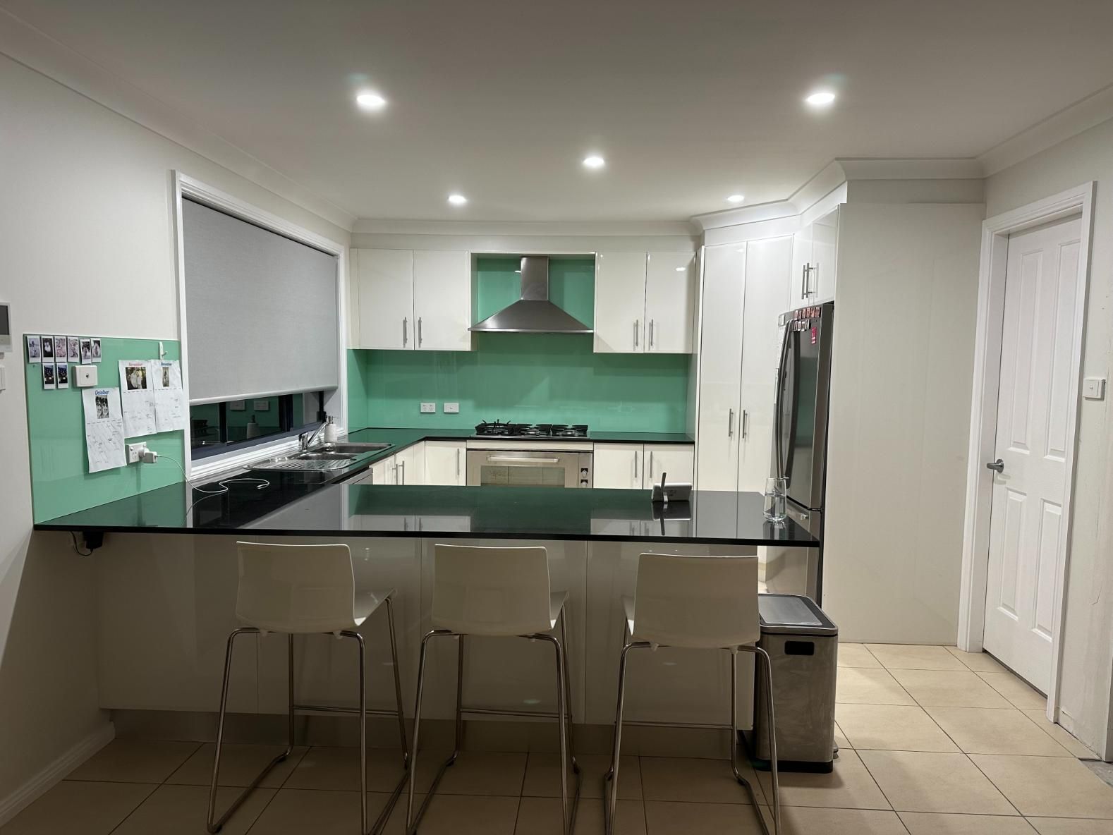 Modern Kitchen with White Cabinets, Black Countertops, Turquoise Backsplash, and Bar Seating — Above & Beyond Interiors Custom Joinery in Mount Anna, NSW
