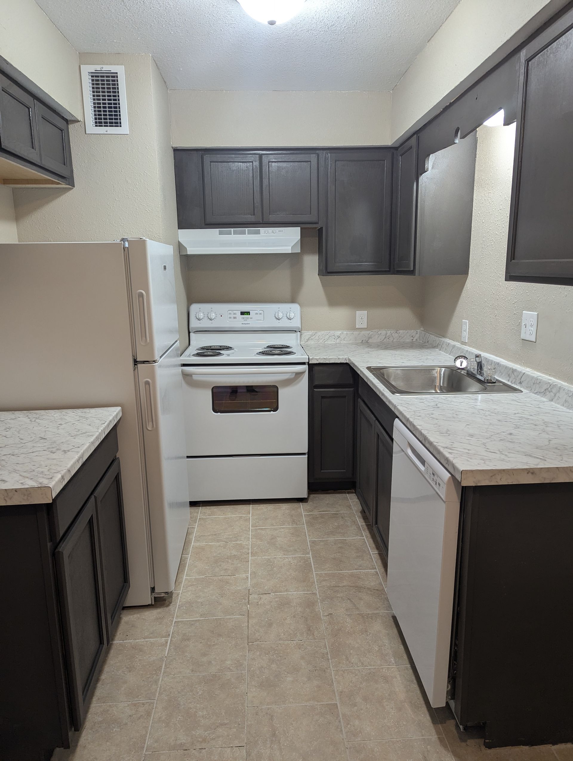 Small kitchen with white appliances, dark cabinets, and light countertops.