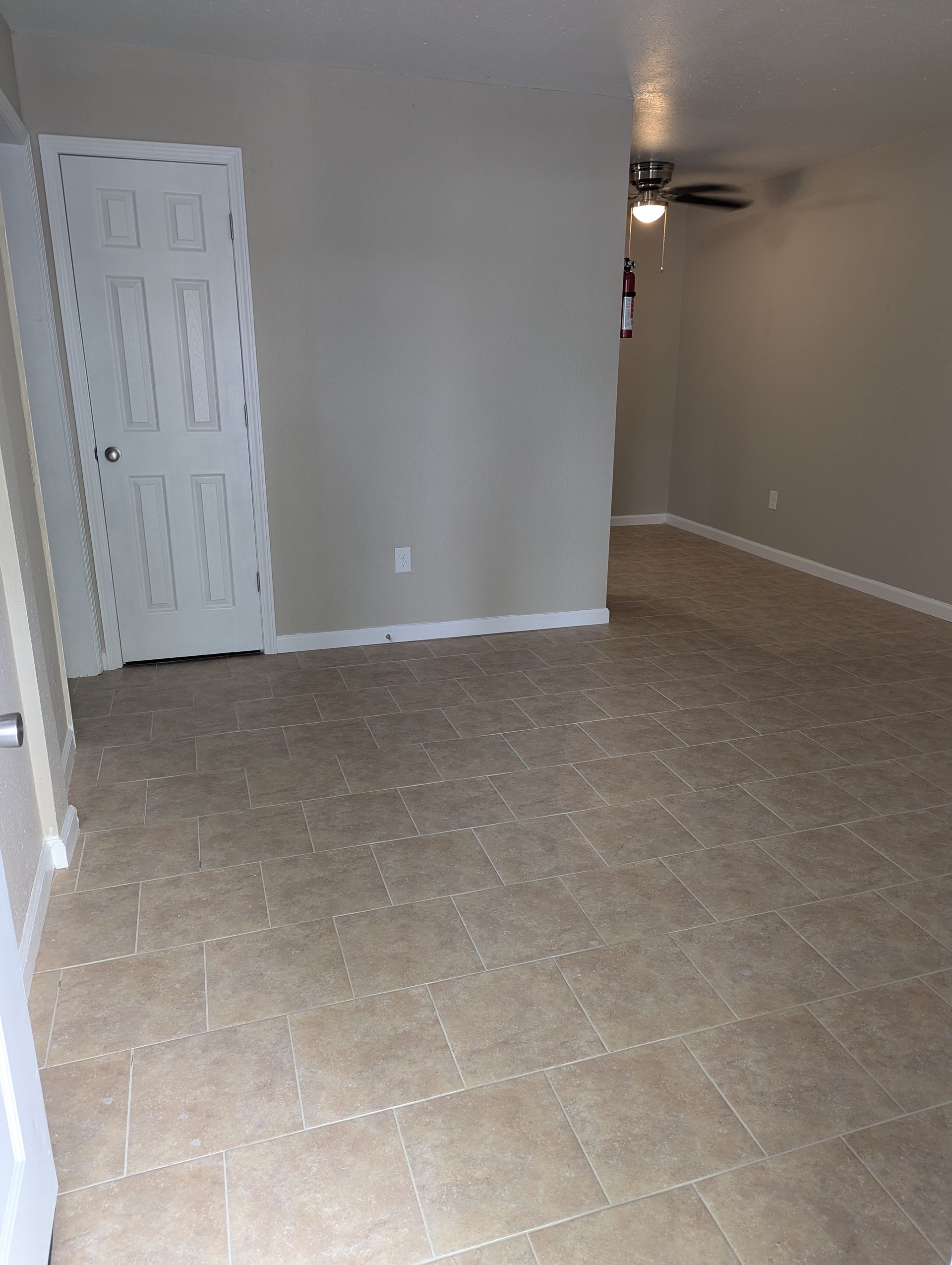 Empty room with tan tile floor, beige walls, and white door.