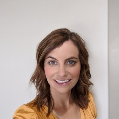 A woman in a yellow shirt is smiling for the camera