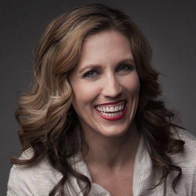 A woman with long hair and red lipstick is smiling for the camera.