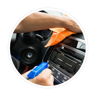 A person is cleaning the dashboard of a car with a cloth.